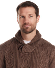 Man wearing a Fisherman Shawl Collar Aran Cable Pullover in Flagstone, featuring a relaxed silhouette and toggle detail.
