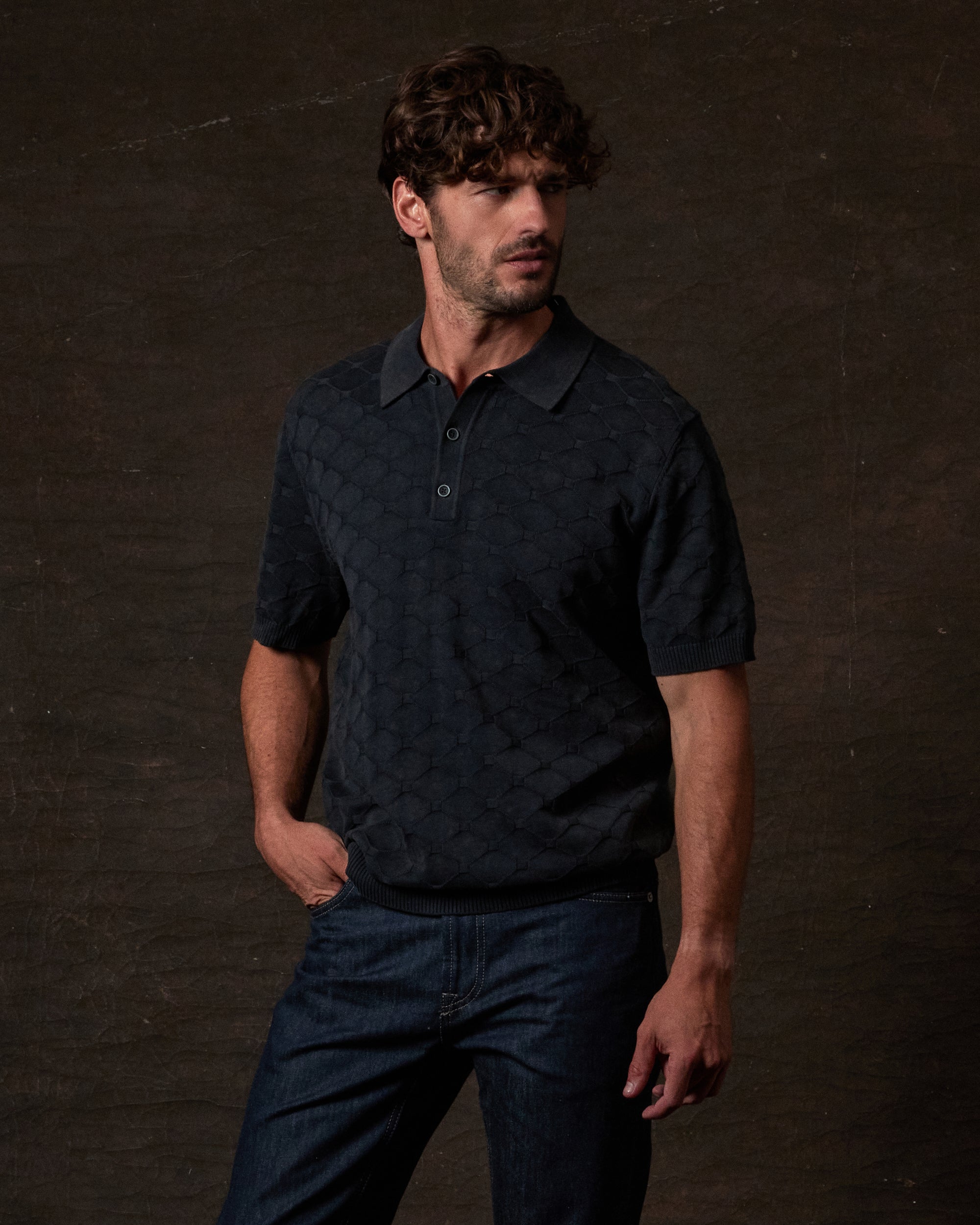 Man wearing a Diamond Sweater Polo in Black against a textured backdrop.