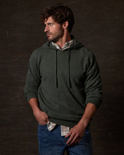 CASHMERE L/S SOLID HOODIE in FOREST GREEN worn by a man, showcasing its luxurious fabric and relaxed fit.