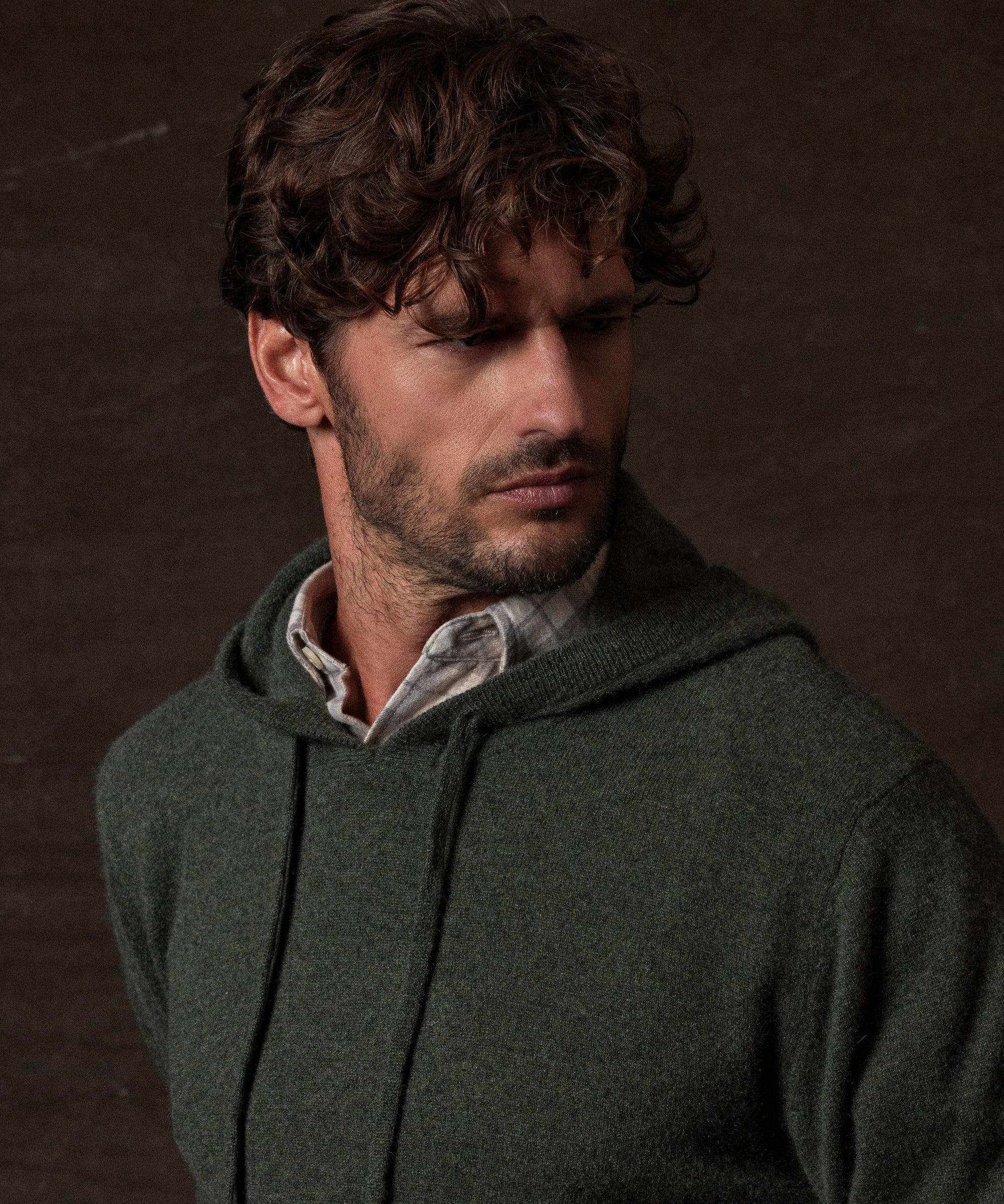 S SOLID HOODIE in FOREST GREEN worn by model against a dark background, showcasing luxury and style.