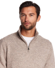 Model wearing a fuzzy quarter zip sweater in taupe, showcasing modern alpine style and a comfortable fit.