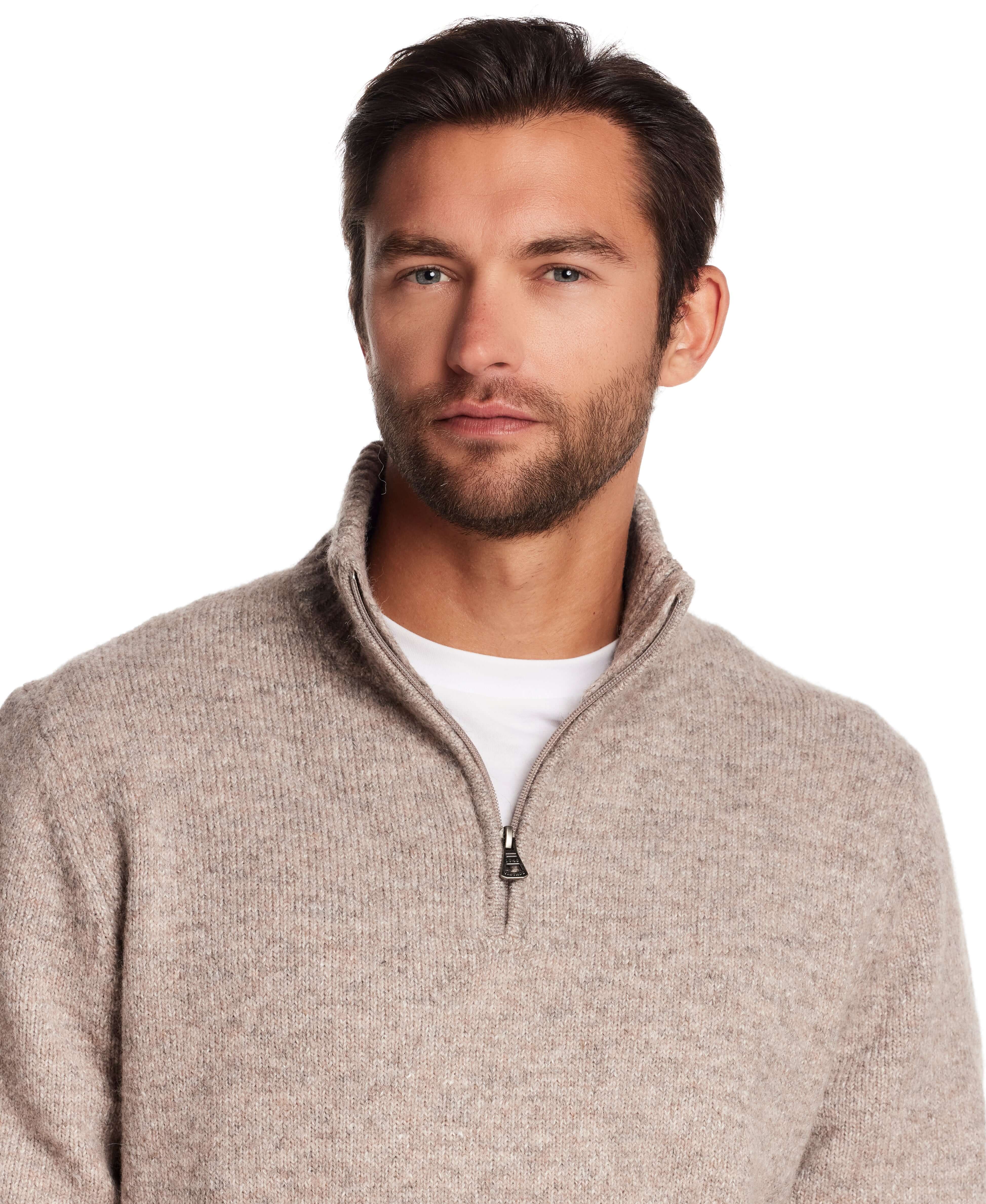 Model wearing a fuzzy quarter zip sweater in taupe, showcasing modern alpine style and a comfortable fit.