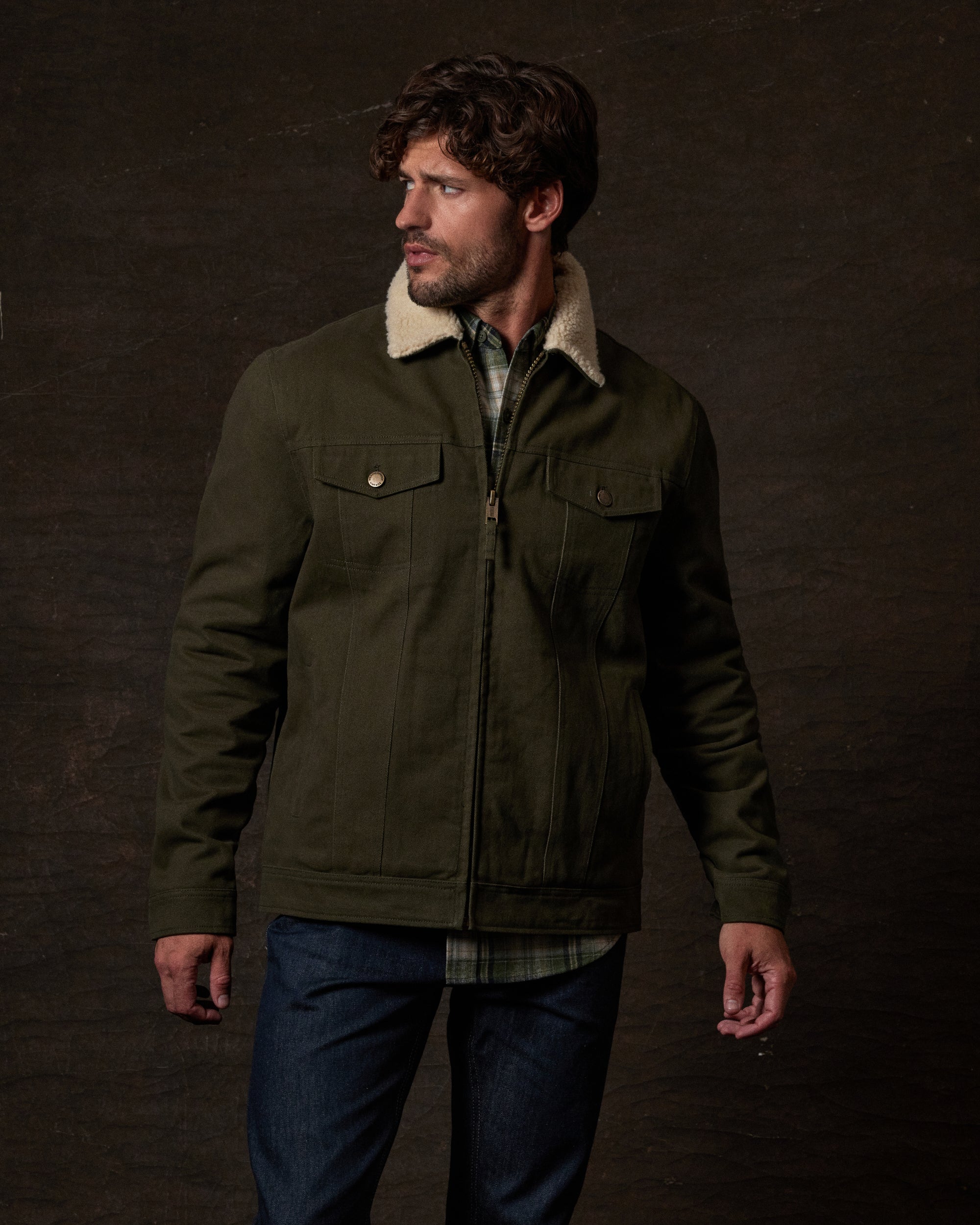 Sherpa Lined Canvas Twill Trucker in Dark Olive worn by a model against a textured background.