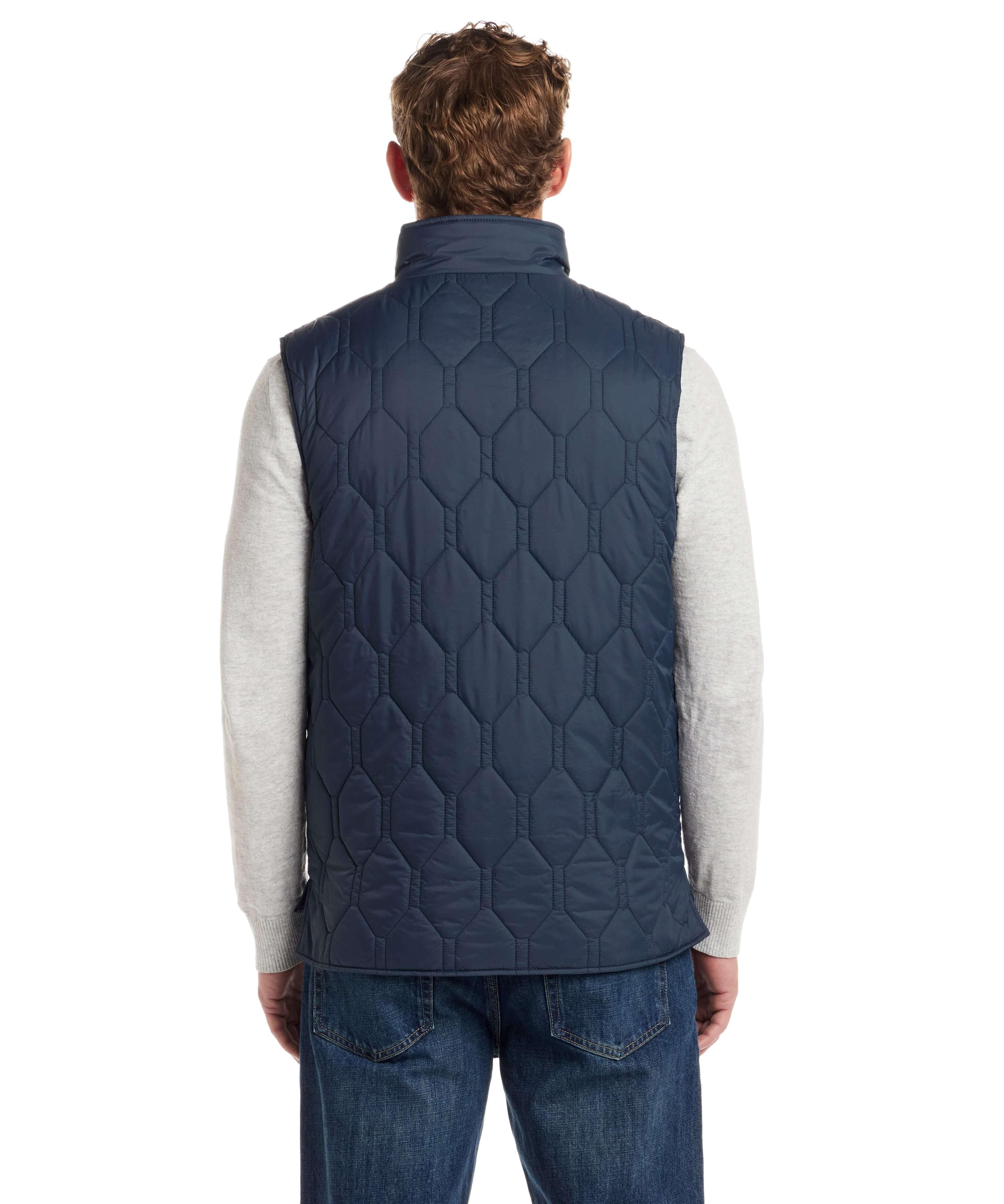Back view of a man wearing a slate blue hexagon quilted lightweight vest over a grey sweater.