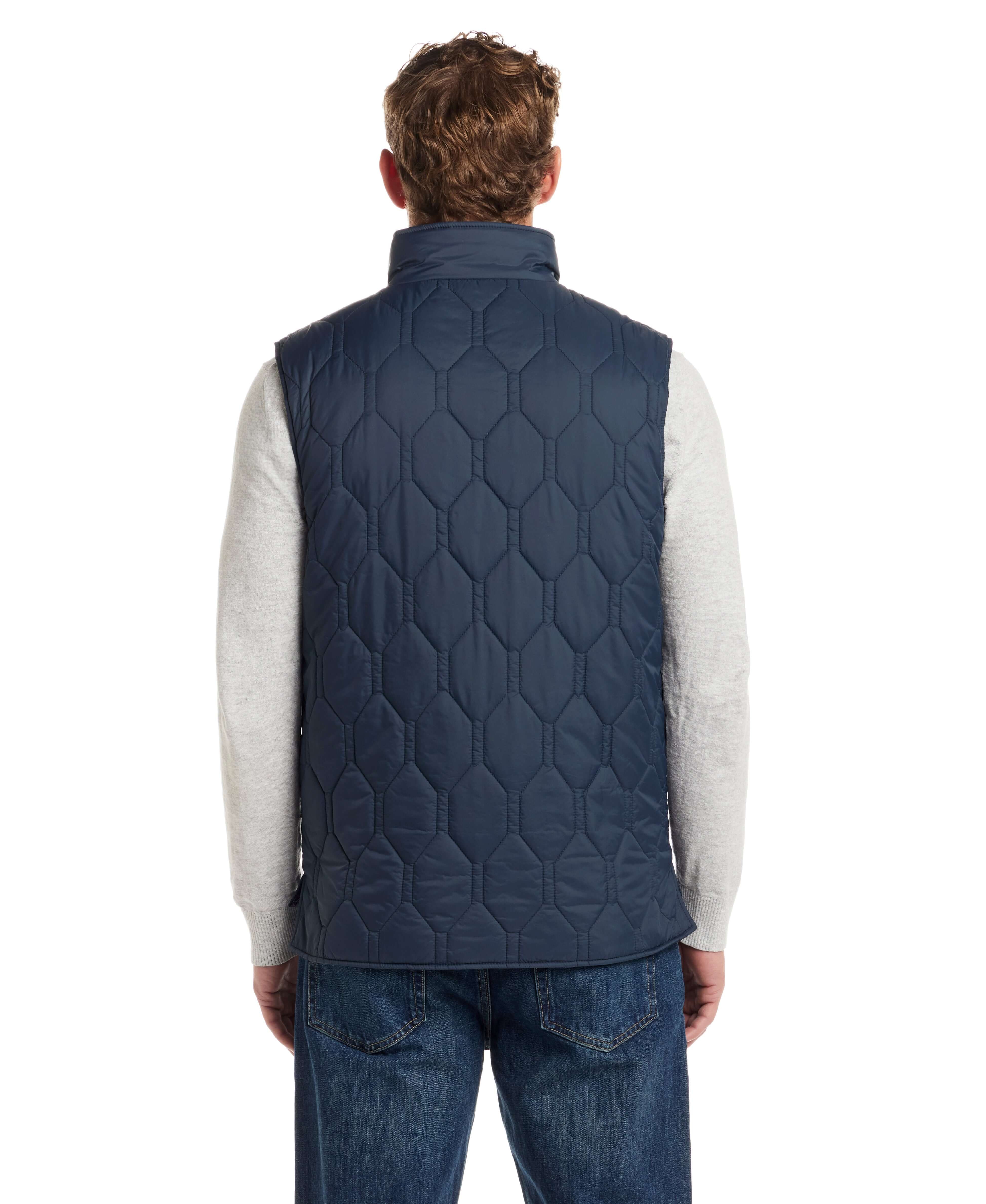 Back view of a man wearing a slate blue hexagon quilted lightweight vest over a grey sweater.