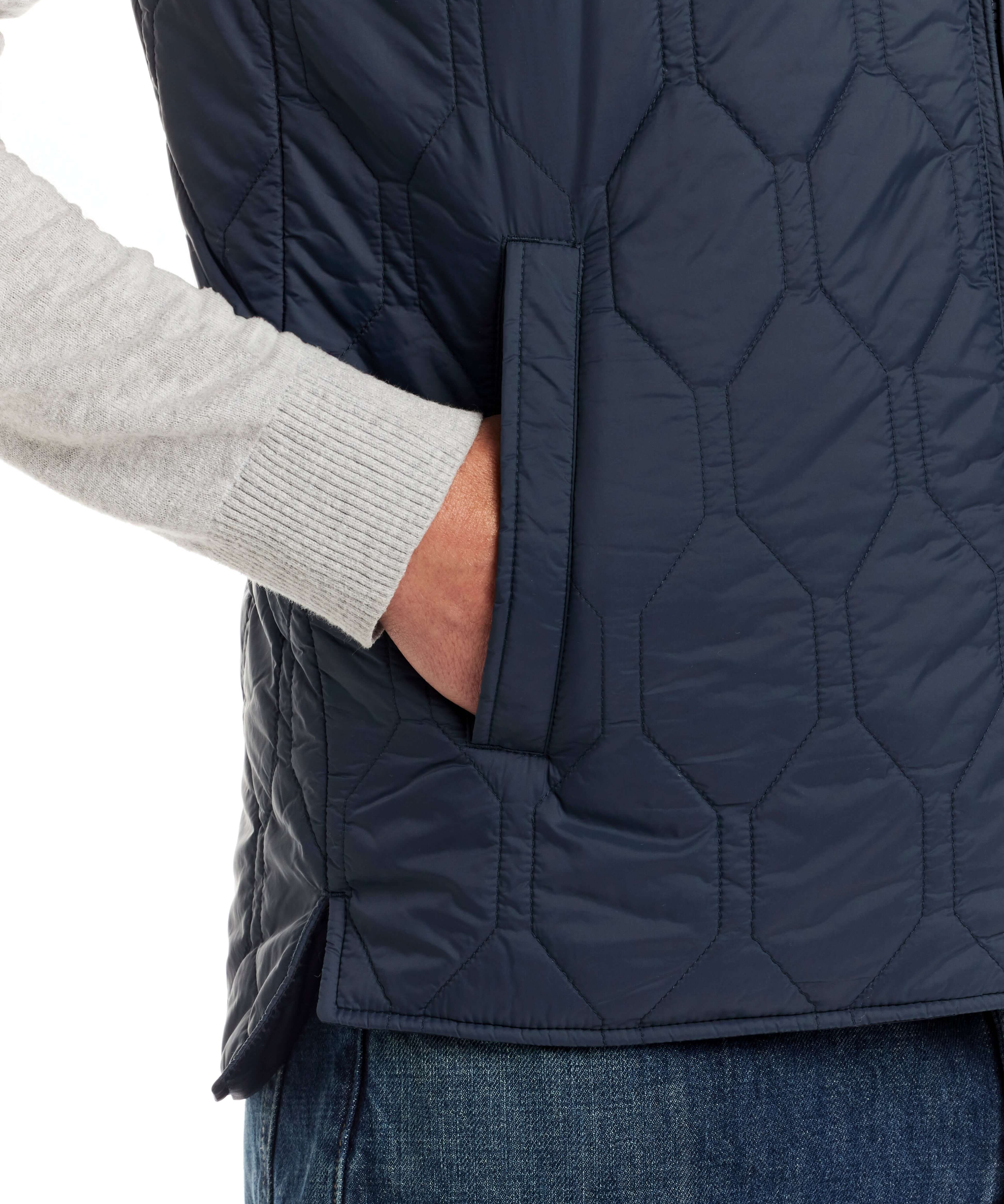 Close-up of hexagon quilted lightweight vest in slate blue with side pocket detail and hand insertion.