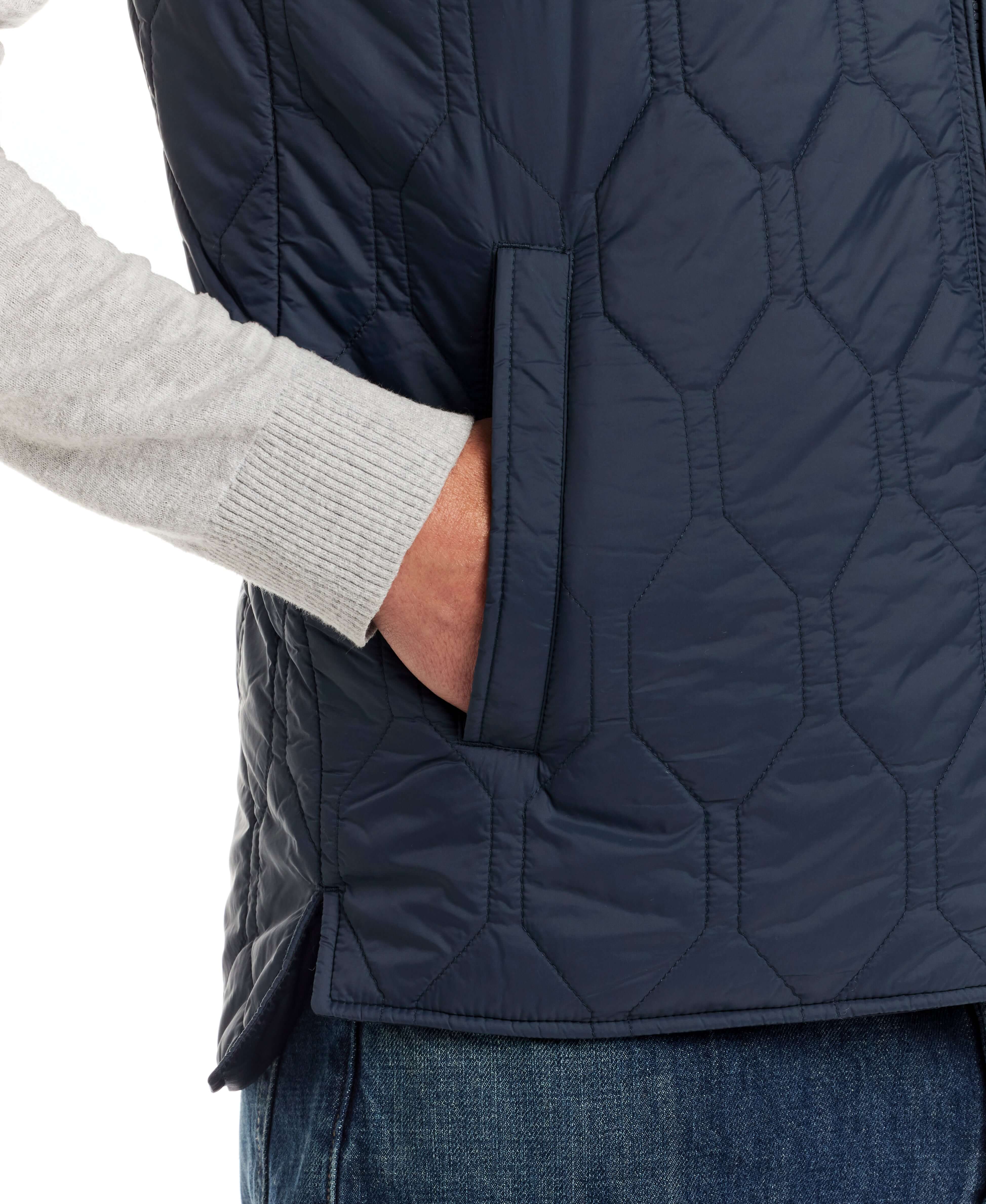 Close-up of hexagon quilted lightweight vest in slate blue with side pocket detail and hand insertion.