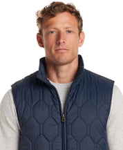 Man wearing a Hexagon Quilted Lightweight Vest in Slate Blue, featuring a front zipper and mock neck.