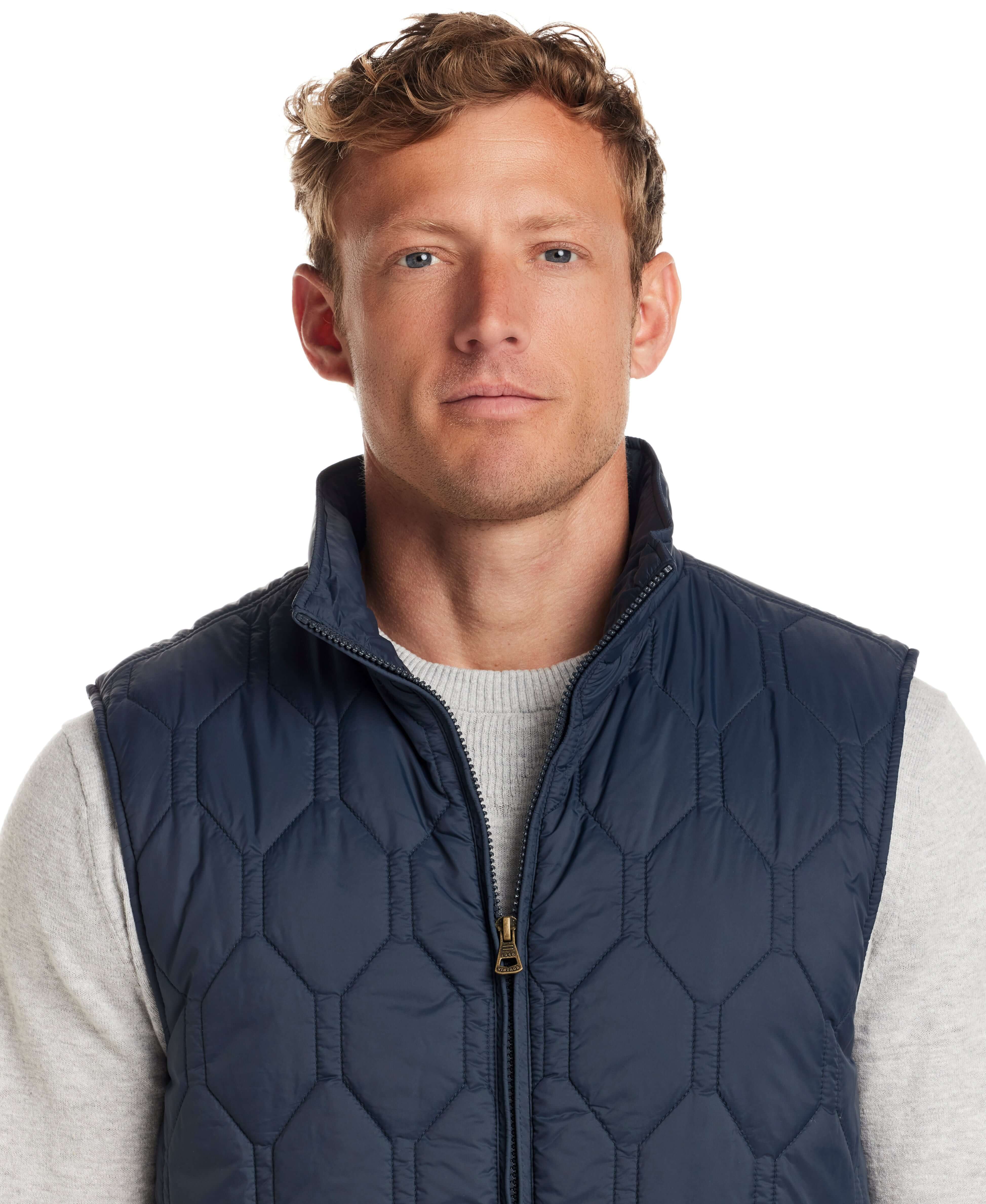 Man wearing a Hexagon Quilted Lightweight Vest in Slate Blue, featuring a front zipper and mock neck.