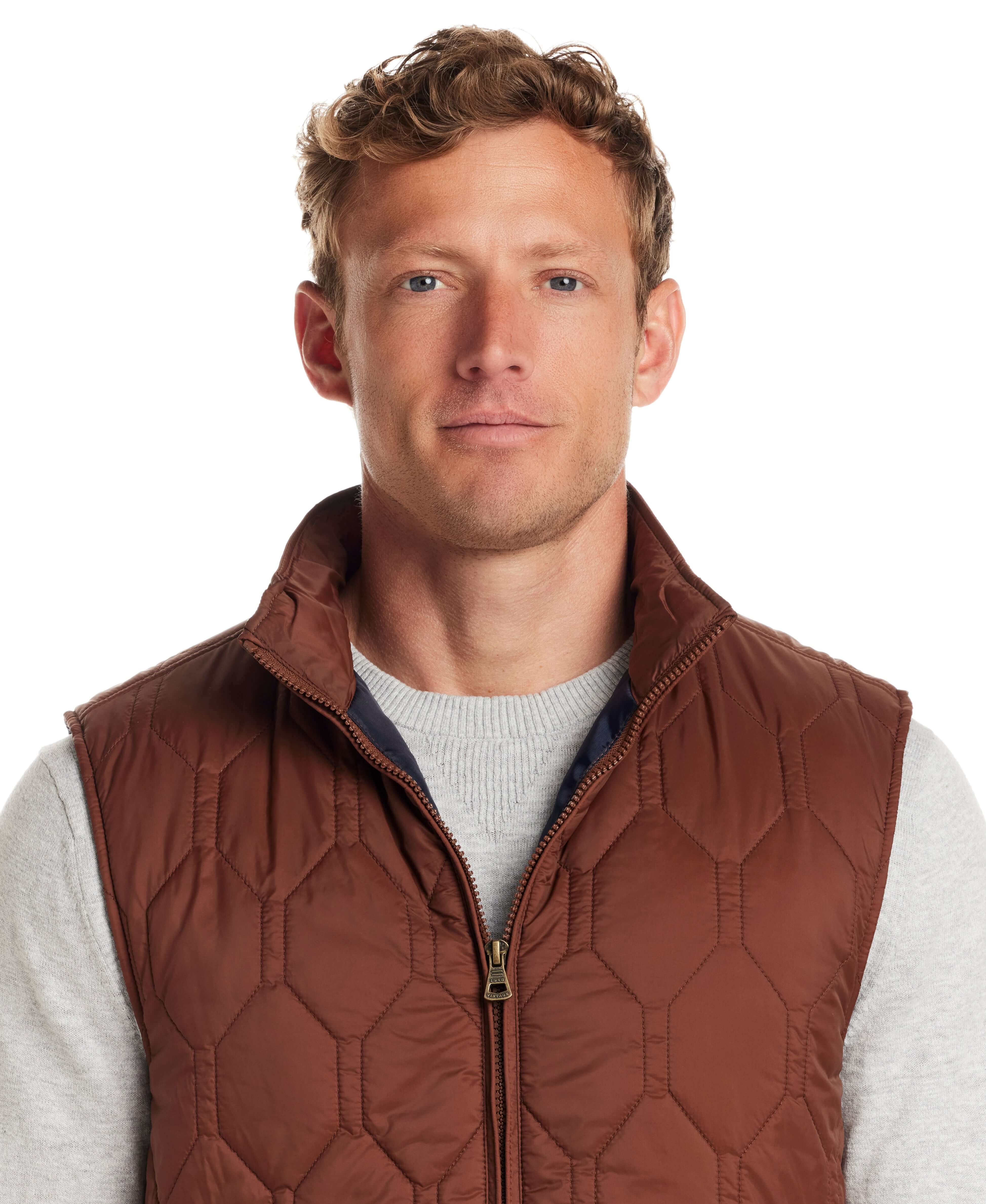 Stylish man wearing a cappuccino hexagon quilted lightweight vest, showcasing its rugged charm and front zipper detail.