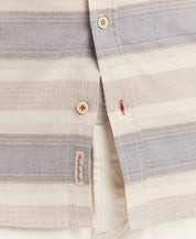 Close-up of a lightweight short-sleeve shirt showcasing a refined dobby weave and button details in soft hues.