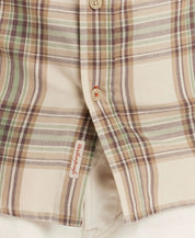 Close-up of a classic long sleeve burnout flannel shirt featuring a cream and green plaid pattern and button details.