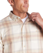 Close-up of a man adjusting the collar of a long sleeve brushed flannel shirt in white and beige check pattern.