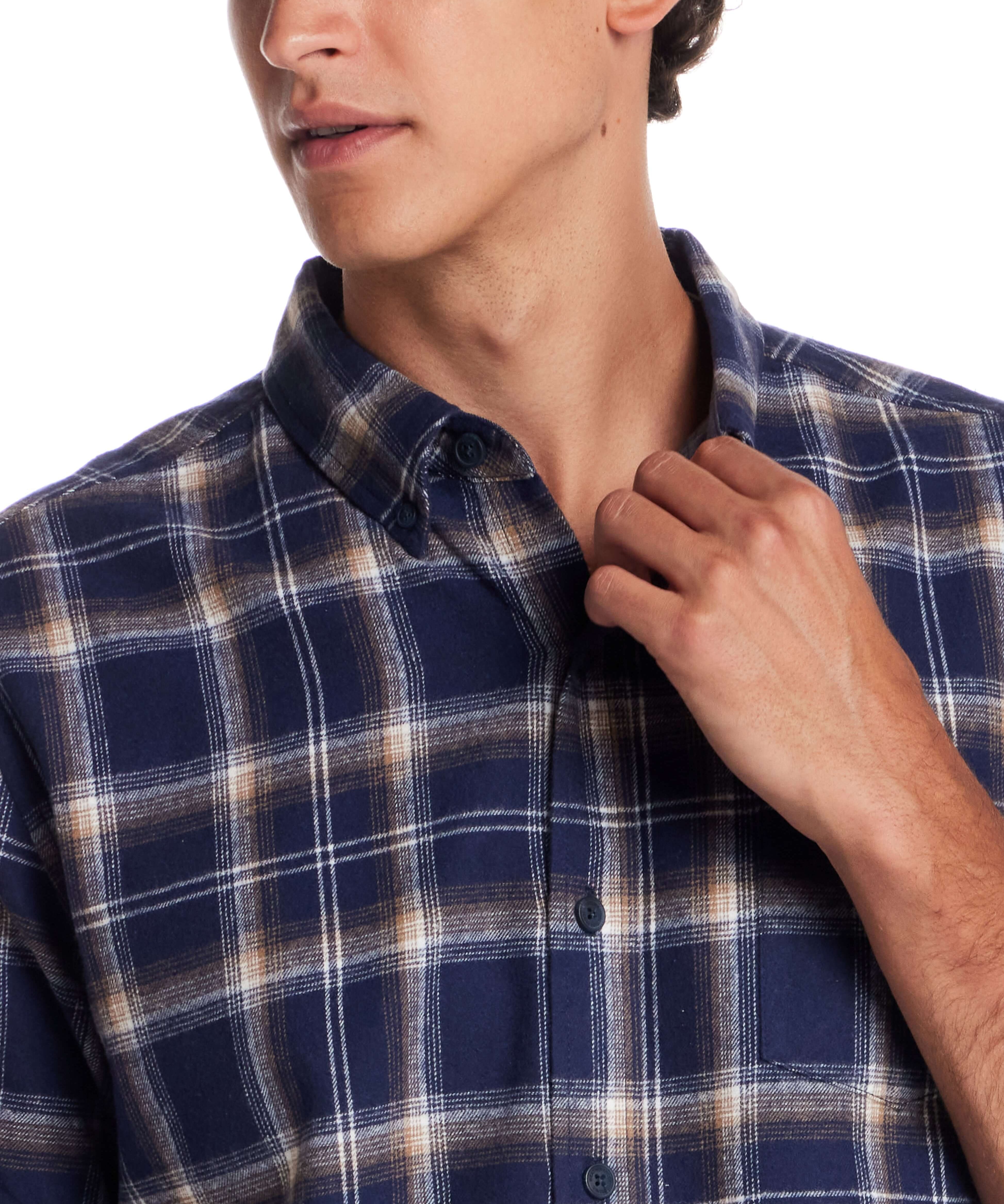 Close-up of a man wearing a long sleeve brushed flannel shirt in Ocean Cavern with button-down collar and plaid pattern.