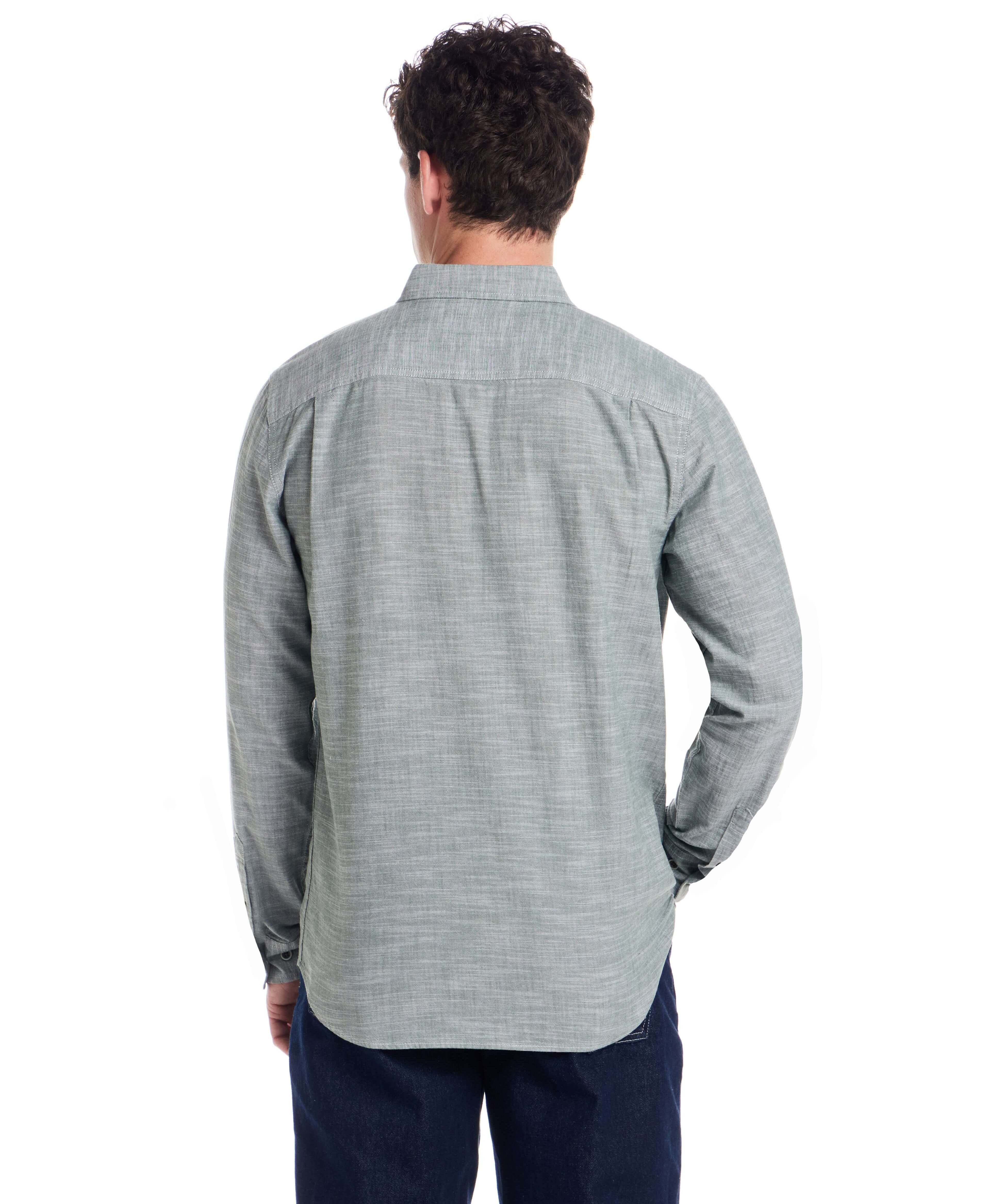Back view of a man wearing a long sleeve chambray button-down shirt in duck green, showcasing the textured fabric.