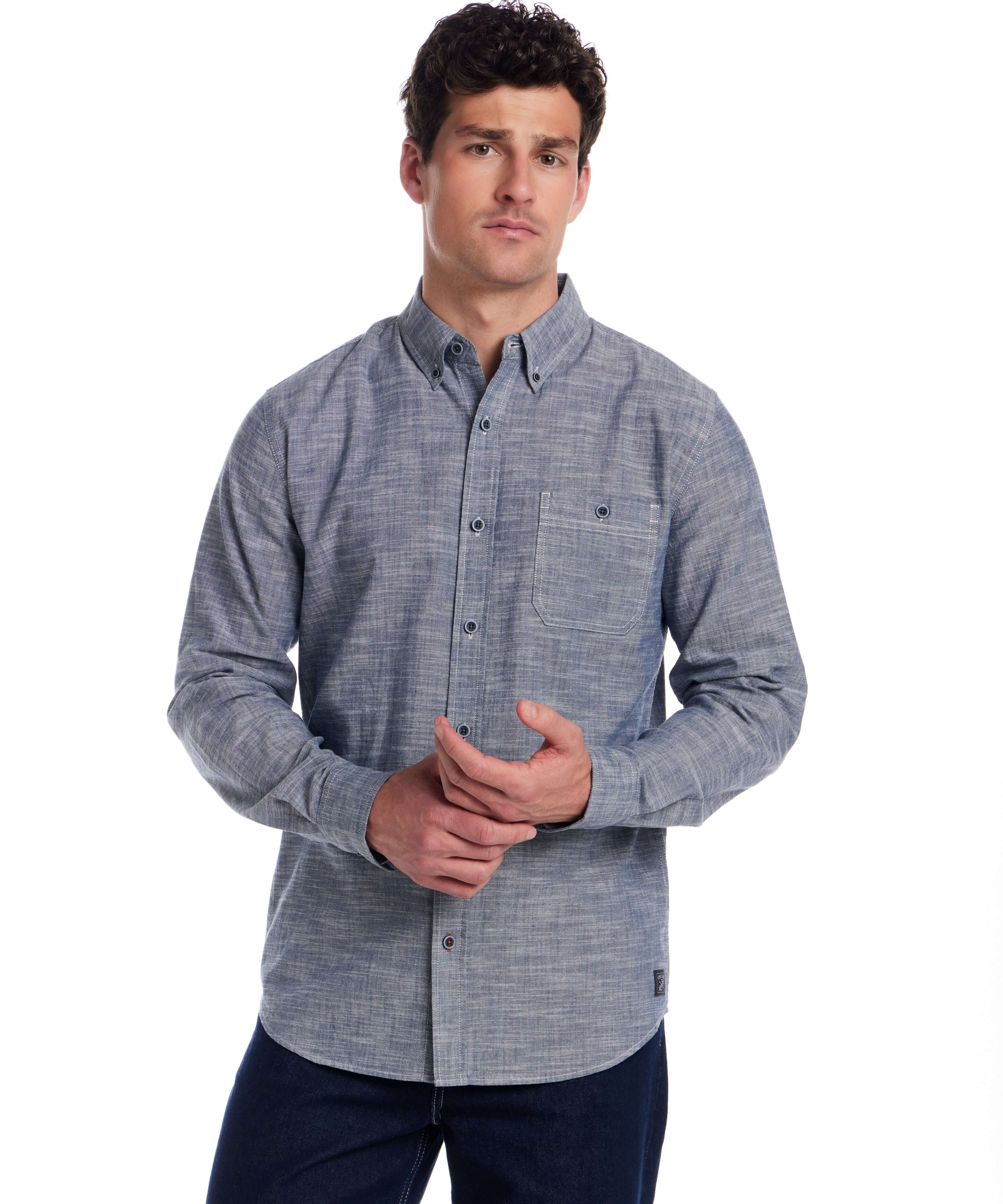 Man wearing a long sleeve chambray button-down shirt in insignia blue, featuring a button-down collar and chest pocket.