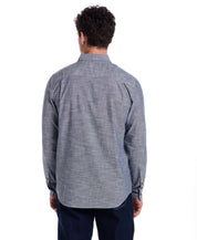 Back view of a man wearing a Long Sleeve Chambray Button-Down shirt in Insignia Blue, showcasing its classic fit and button cuffed sleeves.