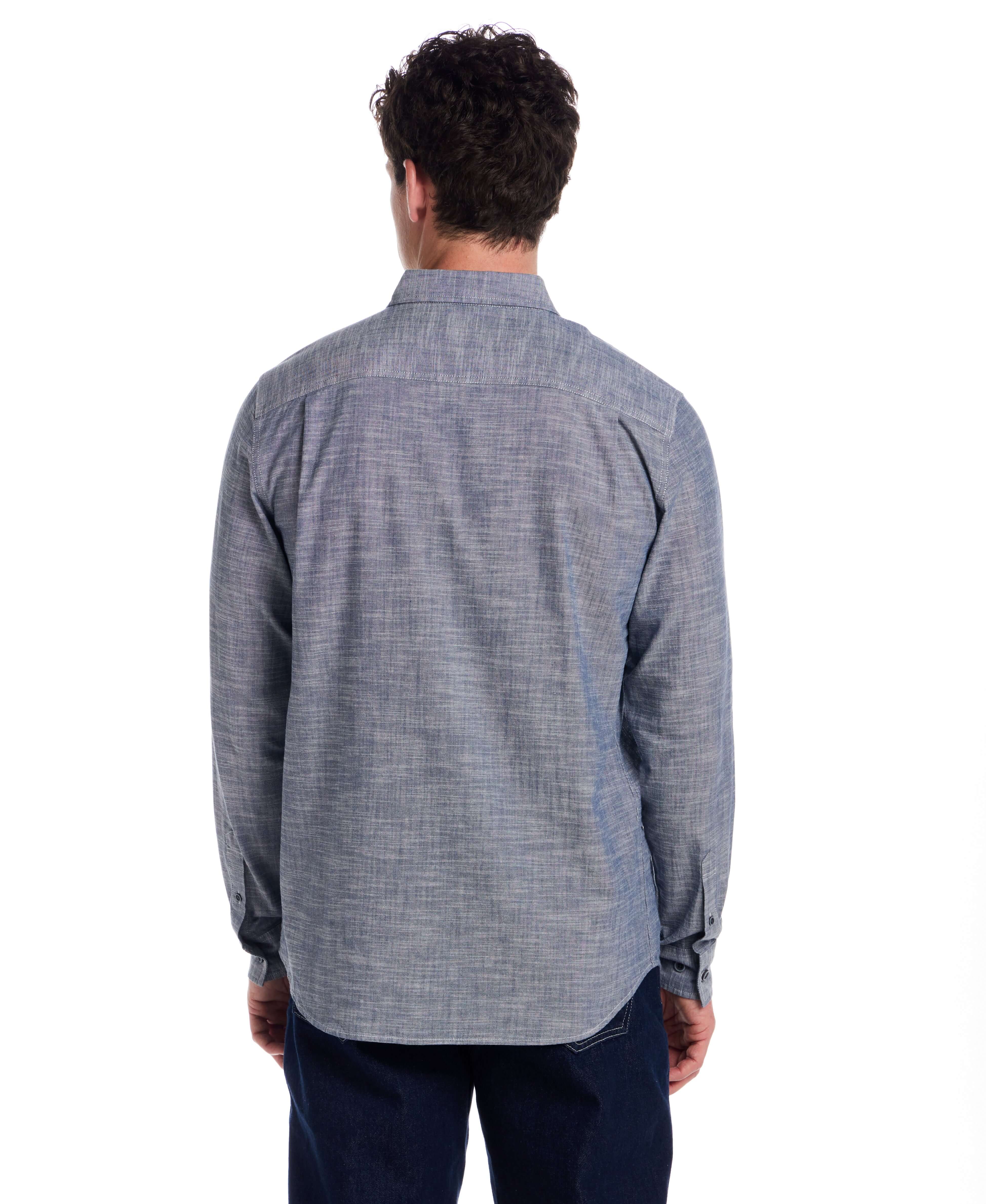 Back view of a man wearing a Long Sleeve Chambray Button-Down shirt in Insignia Blue, showcasing its classic fit and button cuffed sleeves.