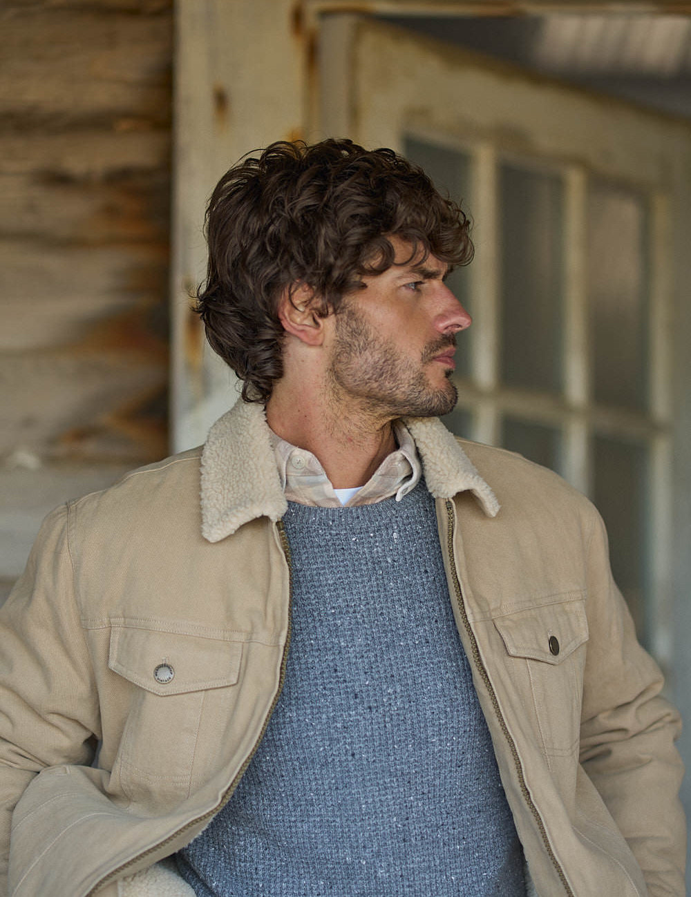 Sherpa Lined Canvas Twill Trucker in White Pepper worn by a man with curly hair in a rustic setting.