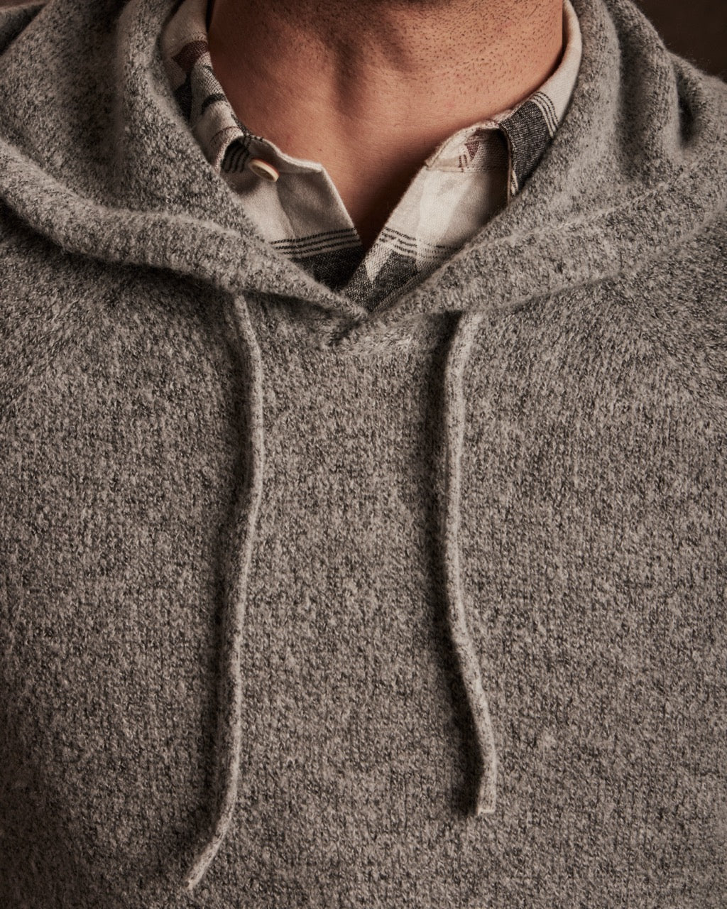 Close-up of a man wearing a Boucle Hoodie Sweater in Winter Sky, showcasing the textured yarn and drawstring details.