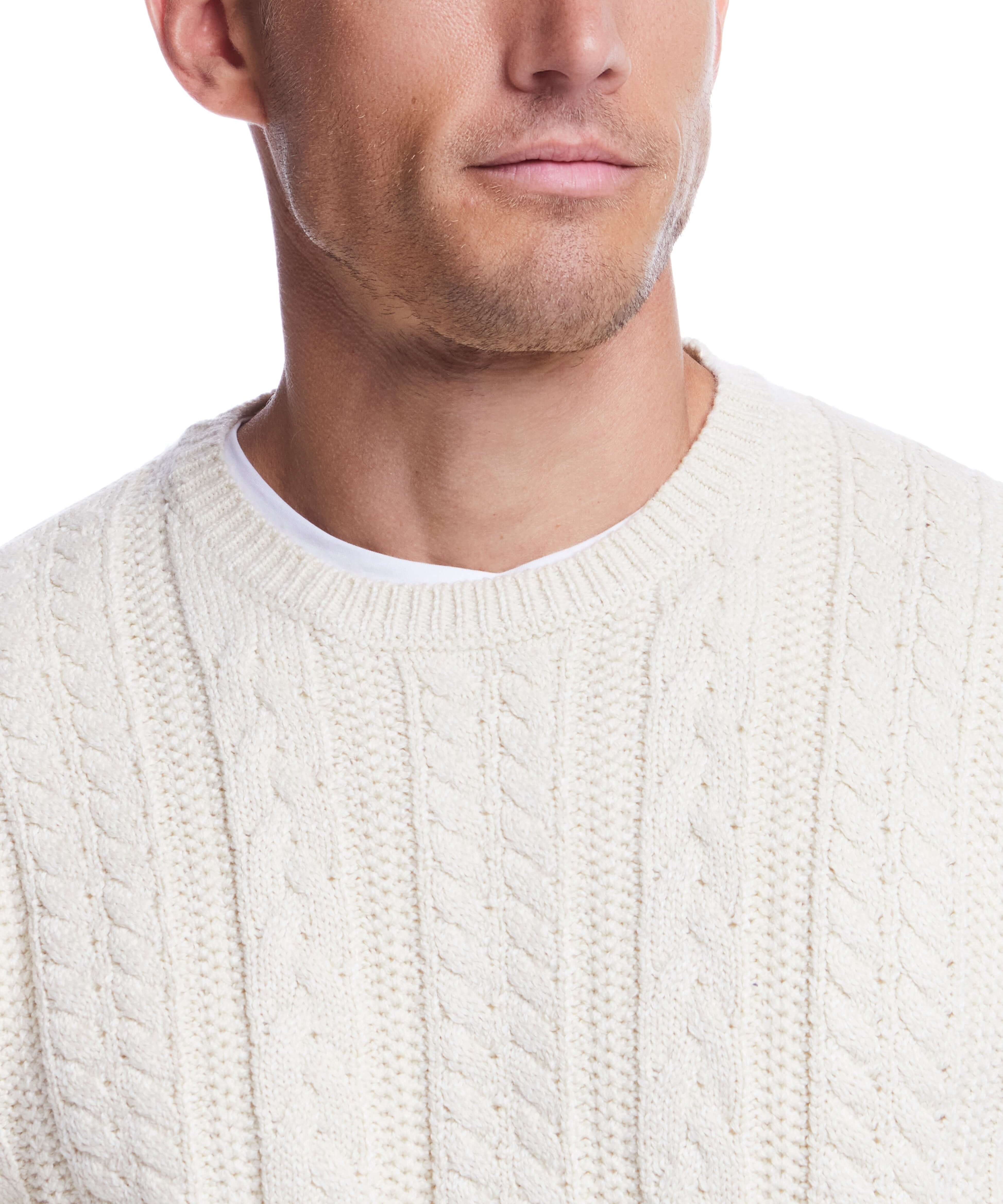 Close-up of a man wearing an allover cable knit crew sweater in white, showcasing its classic design and texture.