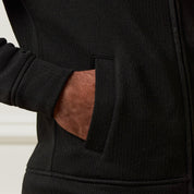 Close-up of a hand in the pocket of a Ribbed Bomber Jacket in Black showcasing the zip-up and ribbed texture.