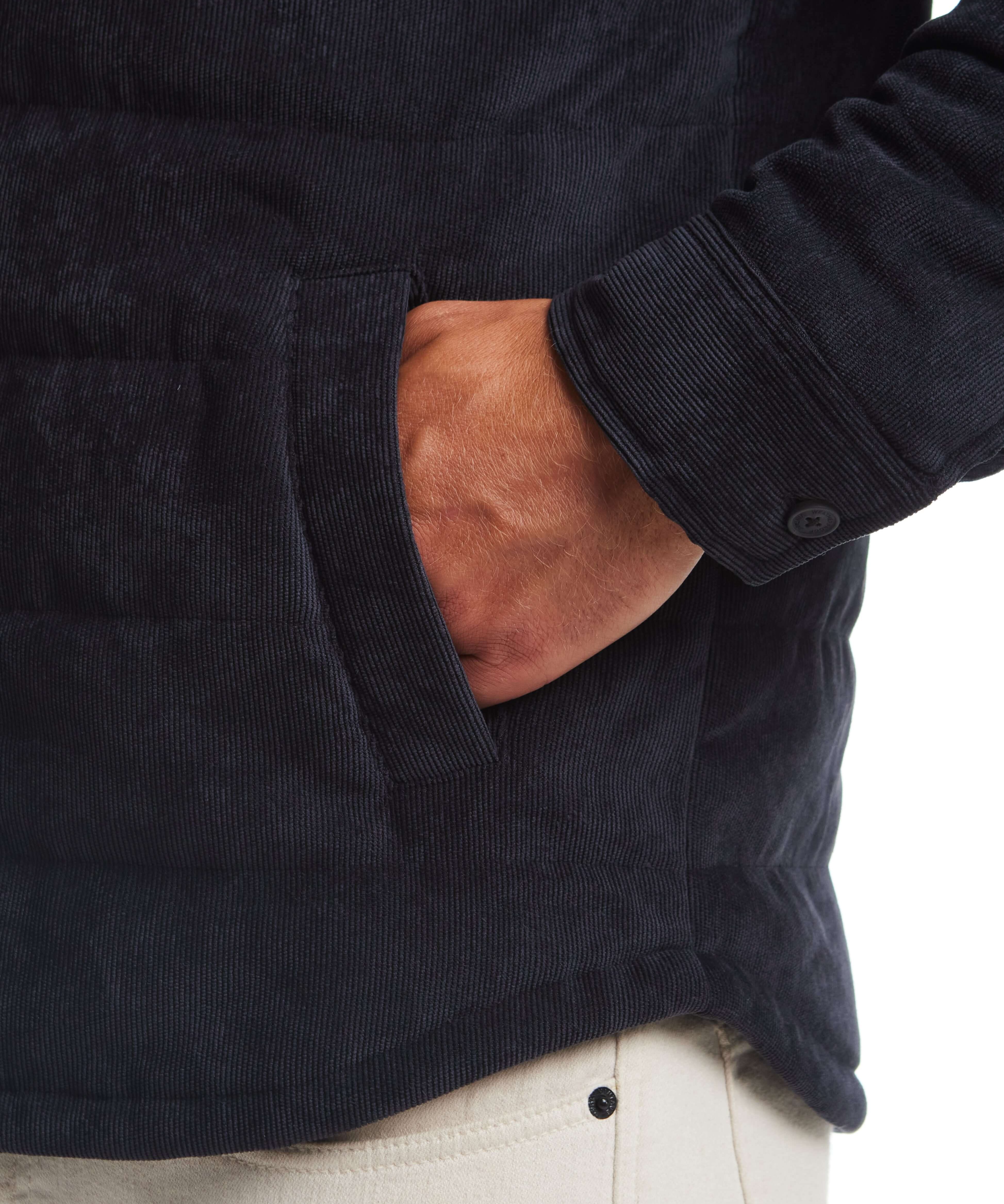 Close-up of a man's hand in the pocket of a corded puffer jacket in moonless night color.