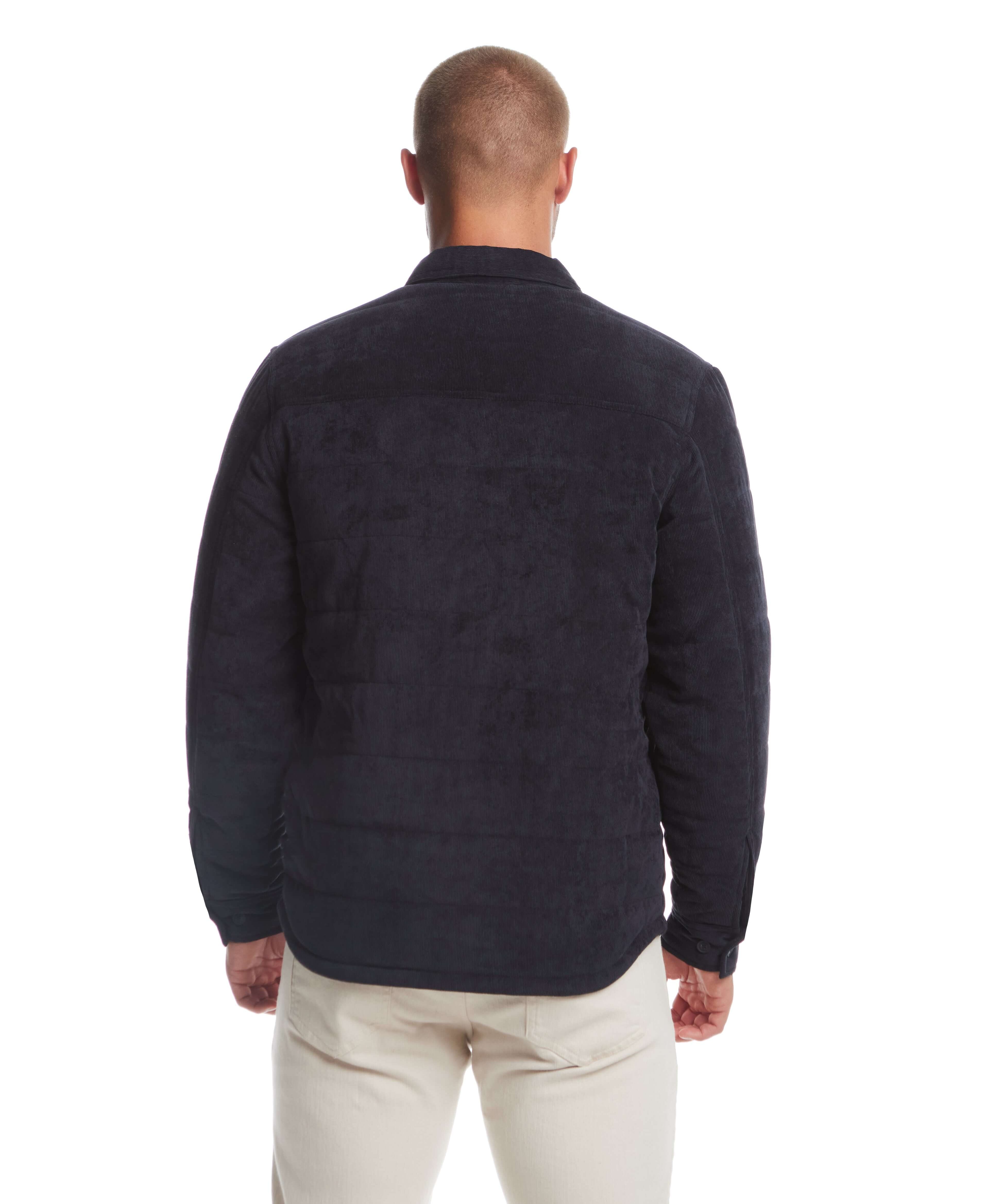 Back view of a man wearing a corded puffer jacket in moonless night, showcasing horizontal quilting and button detailing.
