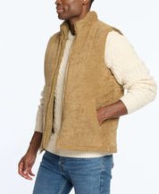 Man wearing a corded puffer vest in kangaroo color, layered over a cream sweater, showcasing a stylish winter look.