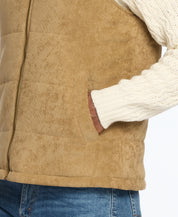 Close-up of a corded puffer vest with shearling lining, highlighting side pocket and texture in warm brown color.