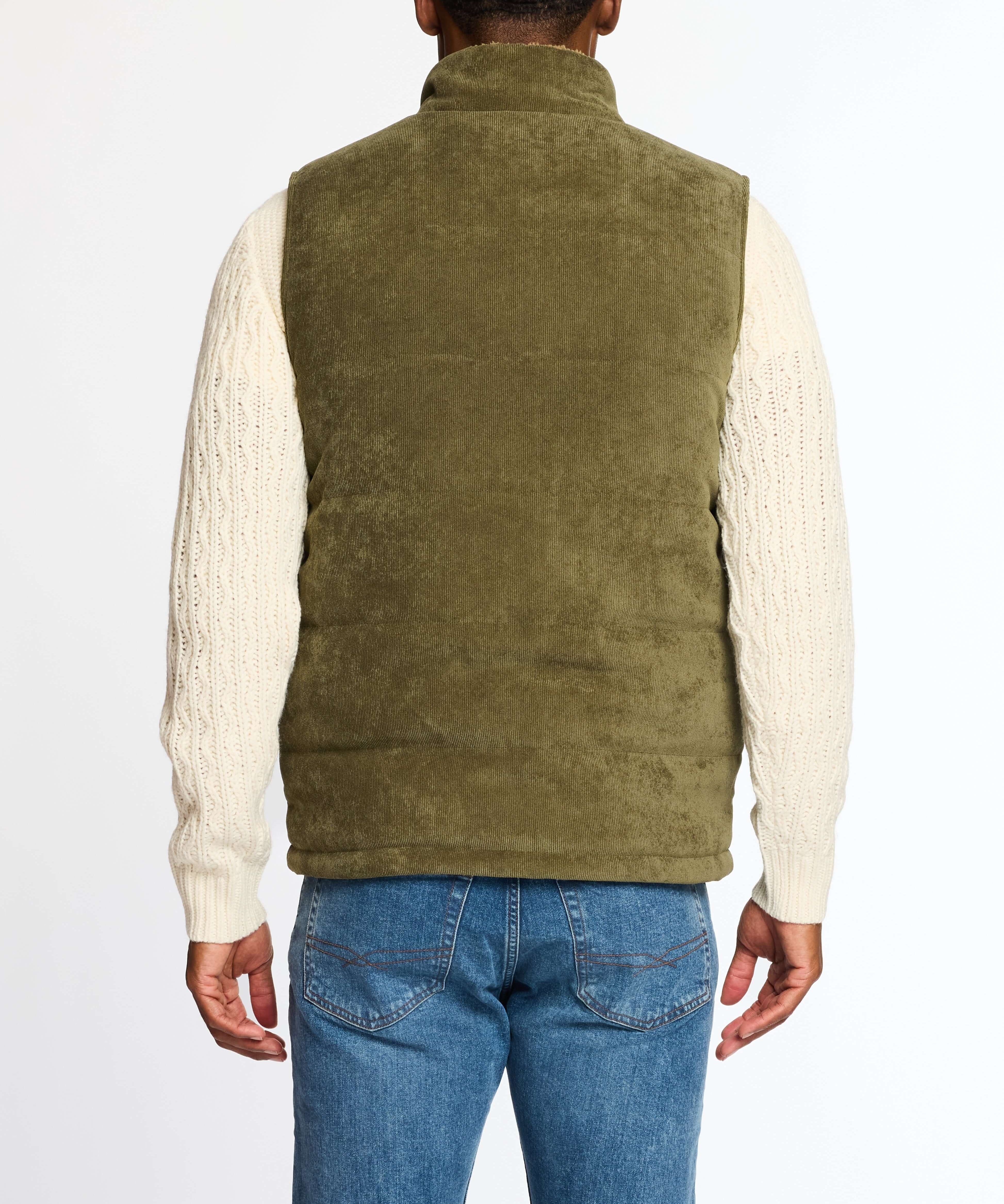 Back view of olive corded puffer vest with shearling lining, worn over a cream-knit sweater and blue jeans.
