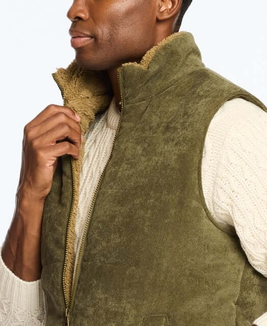 Man wearing a corded puffer vest in olive green with shearling lining, perfect for chilly days and stylish layering.