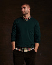 Cotton cashmere holiday v-neck sweater in pine, styled casually over a plaid shirt, modeled by a man.