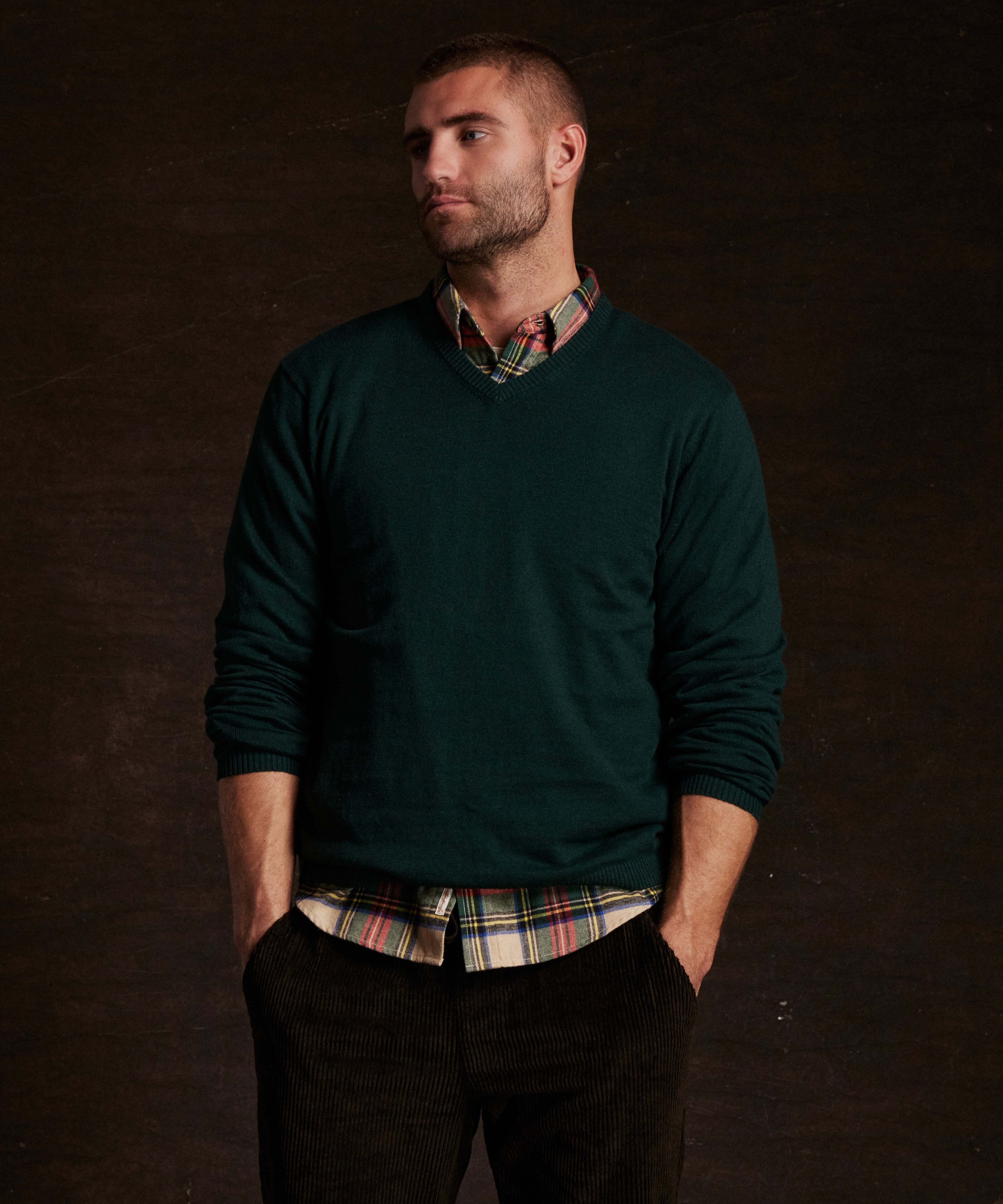 Cotton cashmere holiday v-neck sweater in pine, styled casually over a plaid shirt, modeled by a man.