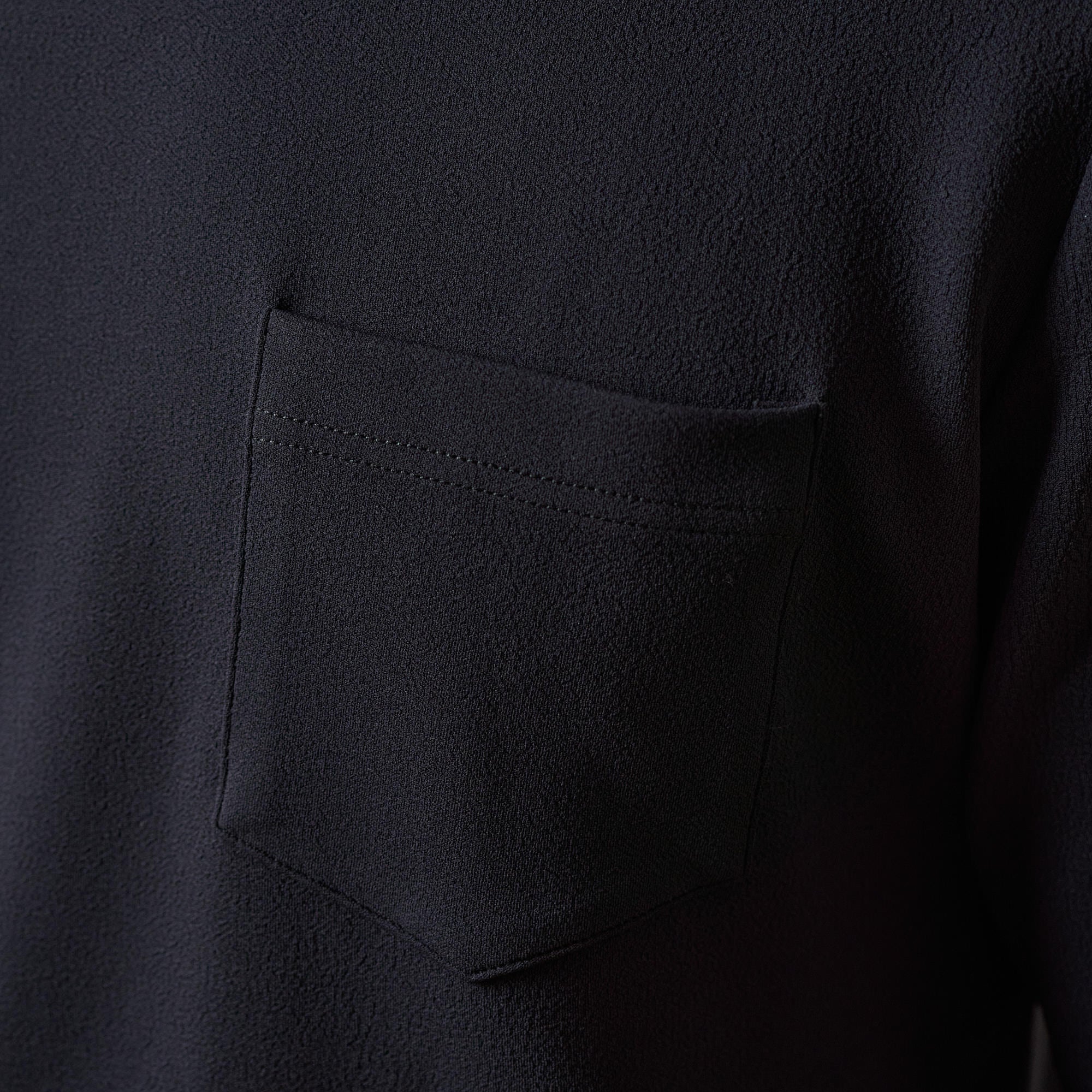 Close-up of the Crinkle Scuba Crew Neck in Black showing pocket detail and soft textured fabric.