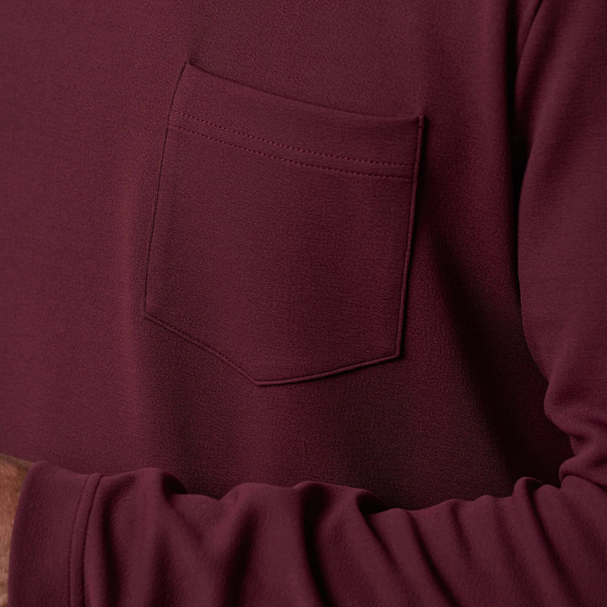 Close-up of the pocket detail on the Crinkle Scuba Crew Neck in Burgundy, showcasing the textured scuba knit fabric.