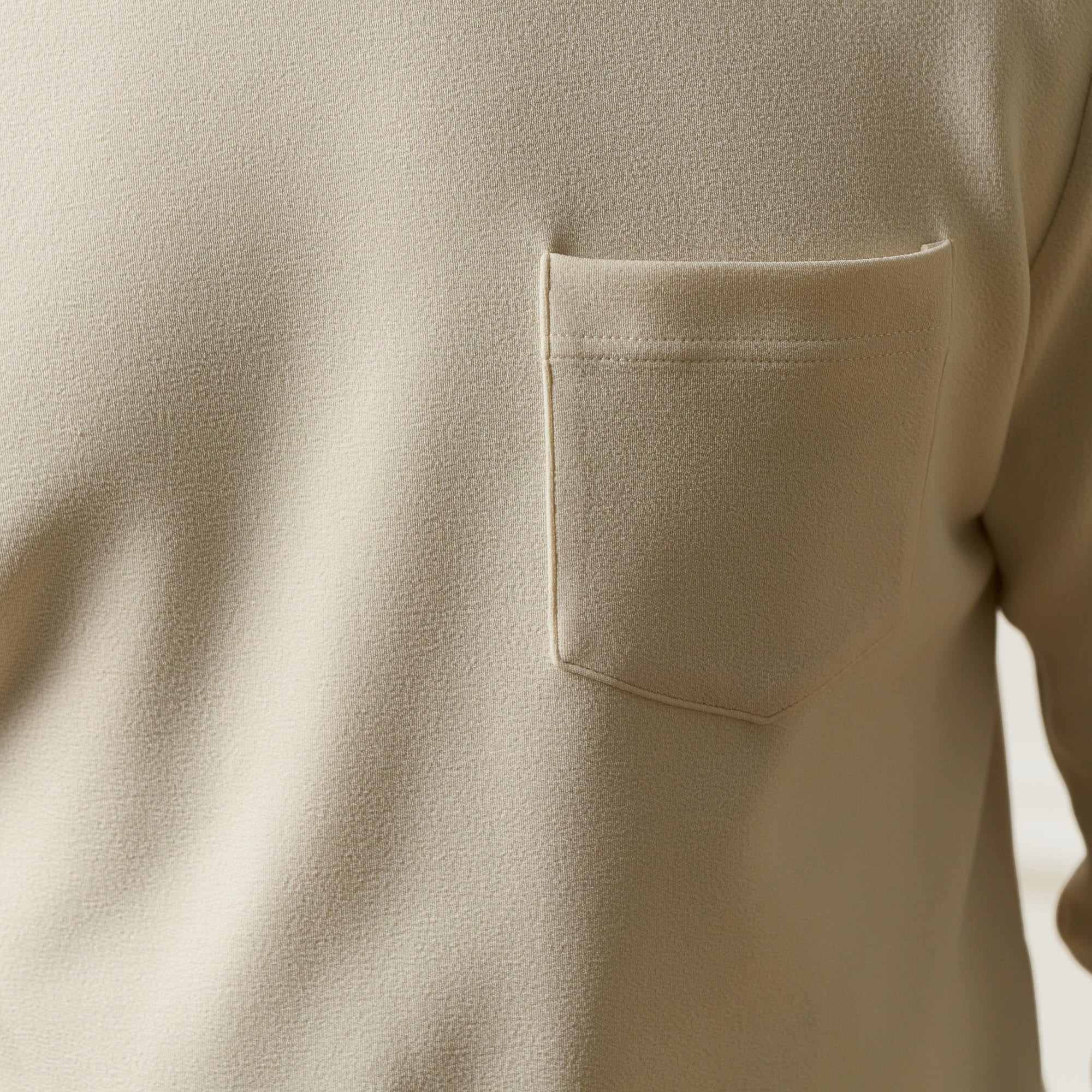 Crinkle Scuba Crew Neck in Ivory showing a textured fabric with a pocket detail.