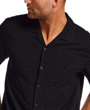 The Dobby Camp Collar Shirt in Black worn by a model, featuring a lightweight rayon texture and chest pocket.