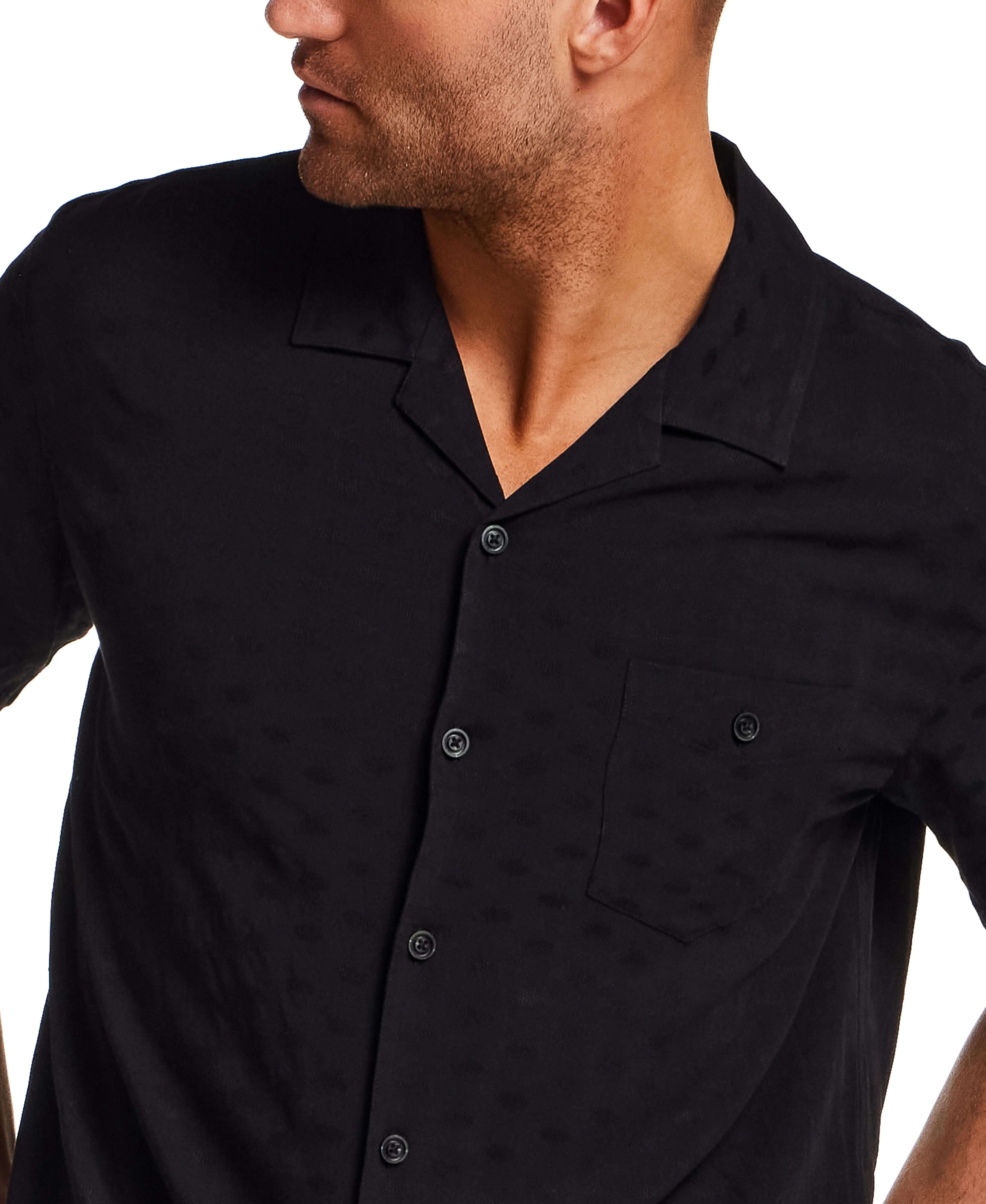 The Dobby Camp Collar Shirt in Black worn by a model, featuring a lightweight rayon texture and chest pocket.