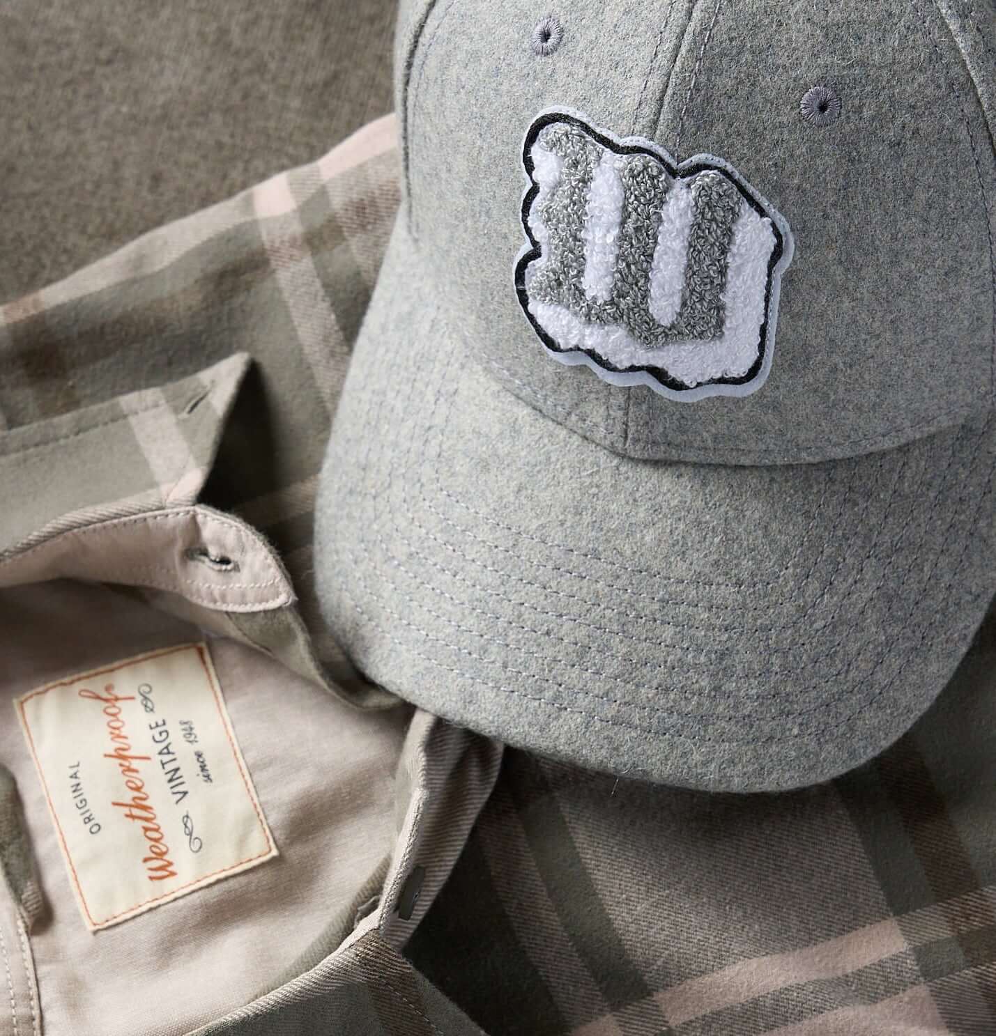 Flannel cap with Appliqué in Light Grey displayed on a plaid shirt, showcasing premium wool craftsmanship.