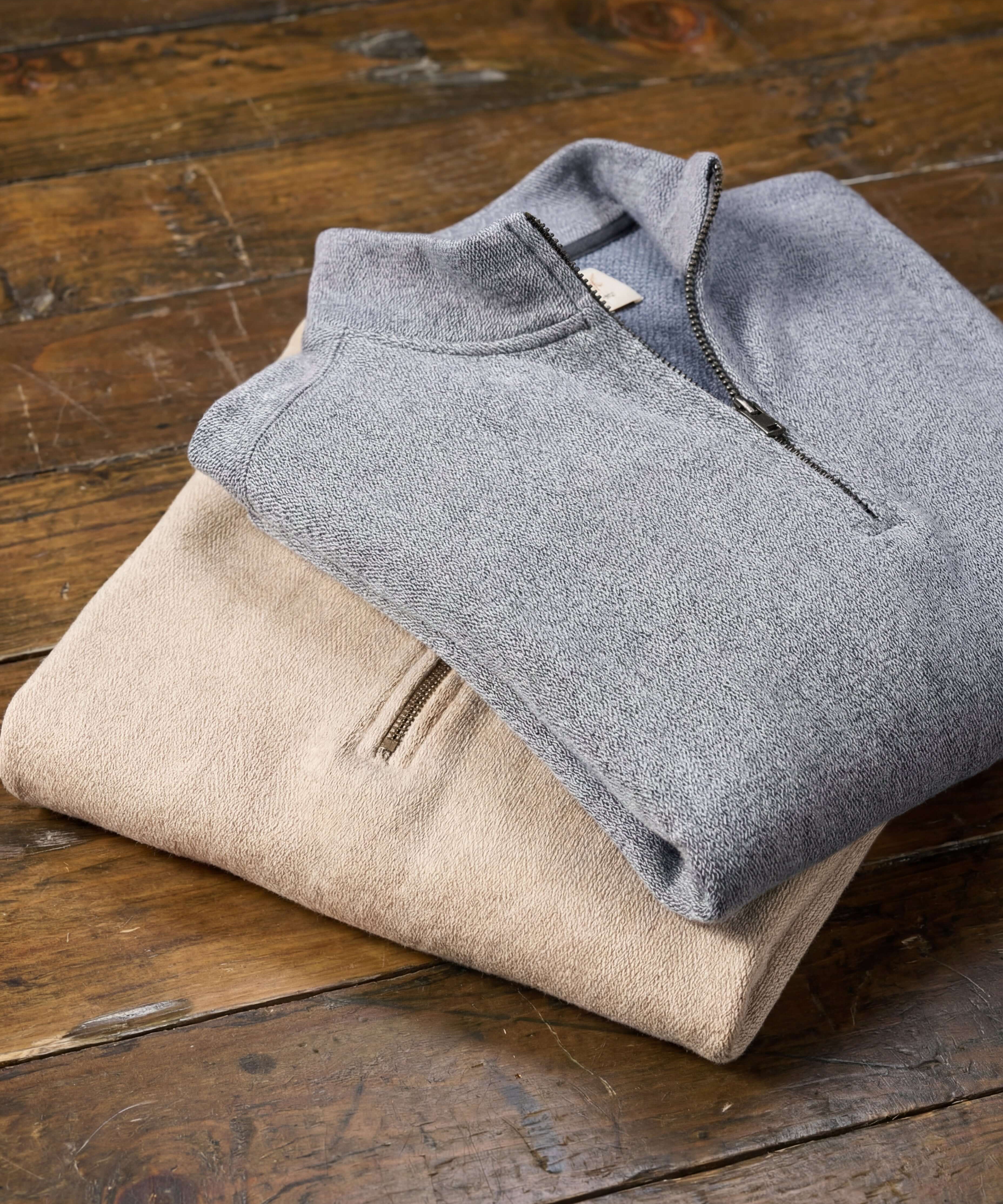 Long Sleeve Quarter Zip in Maritime Blue and beige pullover stacked on wooden table.