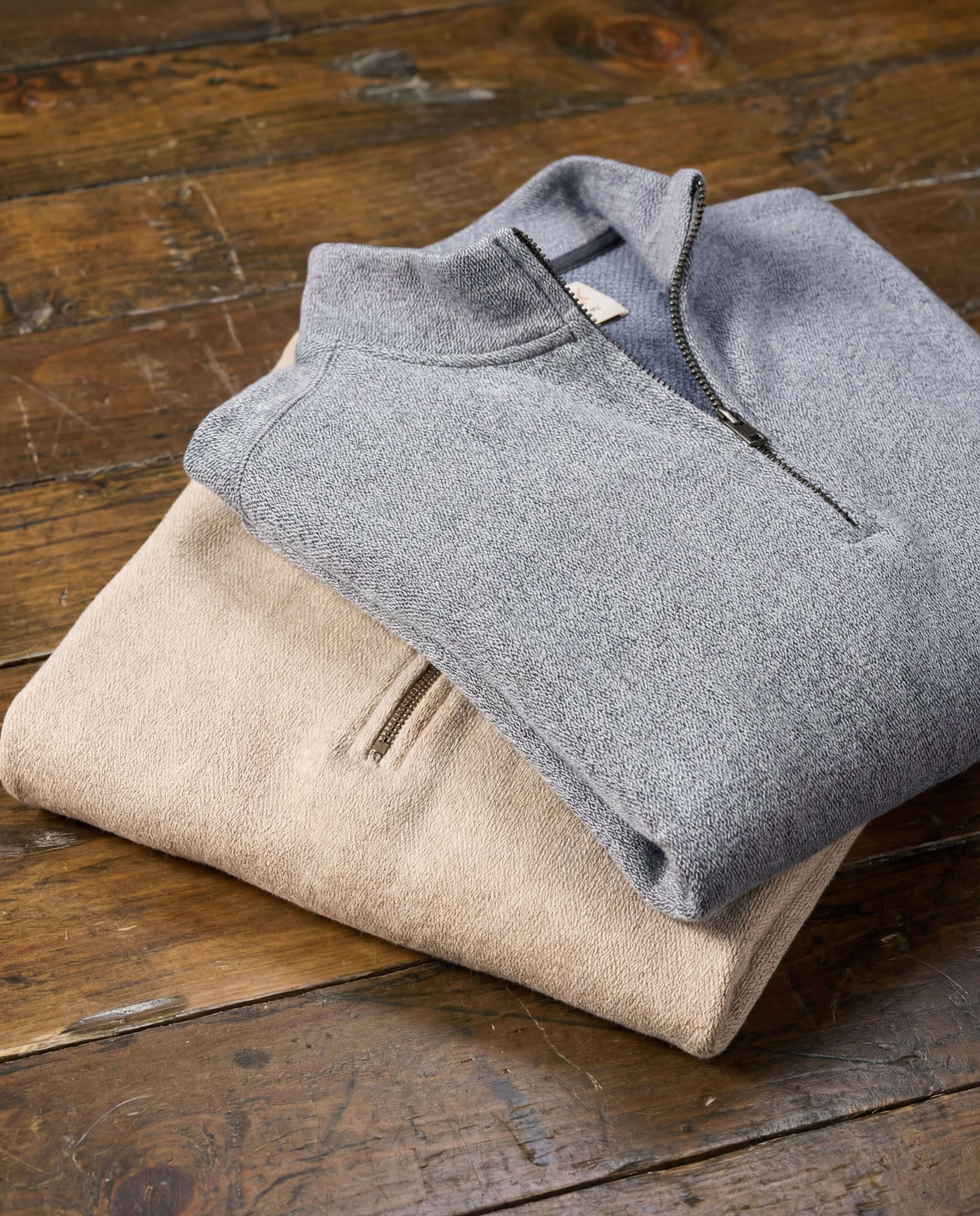 Long Sleeve Quarter Zip in Maritime Blue and beige pullover stacked on wooden table.