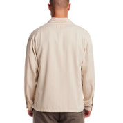 Back view of a man wearing a long sleeve unlined utility shirt jacket in white pepper, showcasing its herringbone pattern.