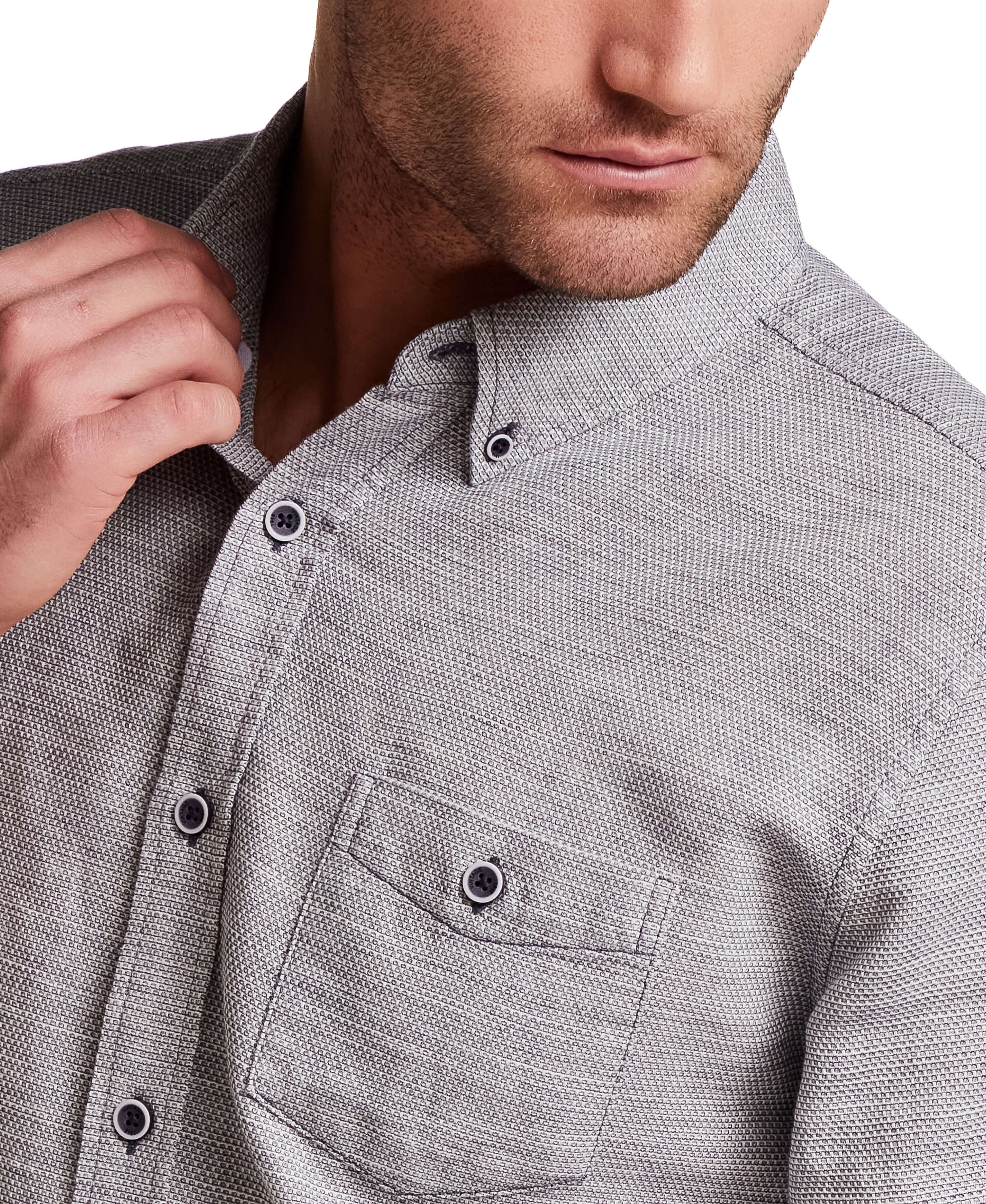 Close-up of a man wearing a Pebble Dobby Button-Down Shirt in Maritime Blue, showcasing the textured fabric and button-down collar.