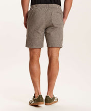 Back view of a man wearing Chambray Stripe Drawstring Short in Black Stripe with a striped pattern and side pockets.