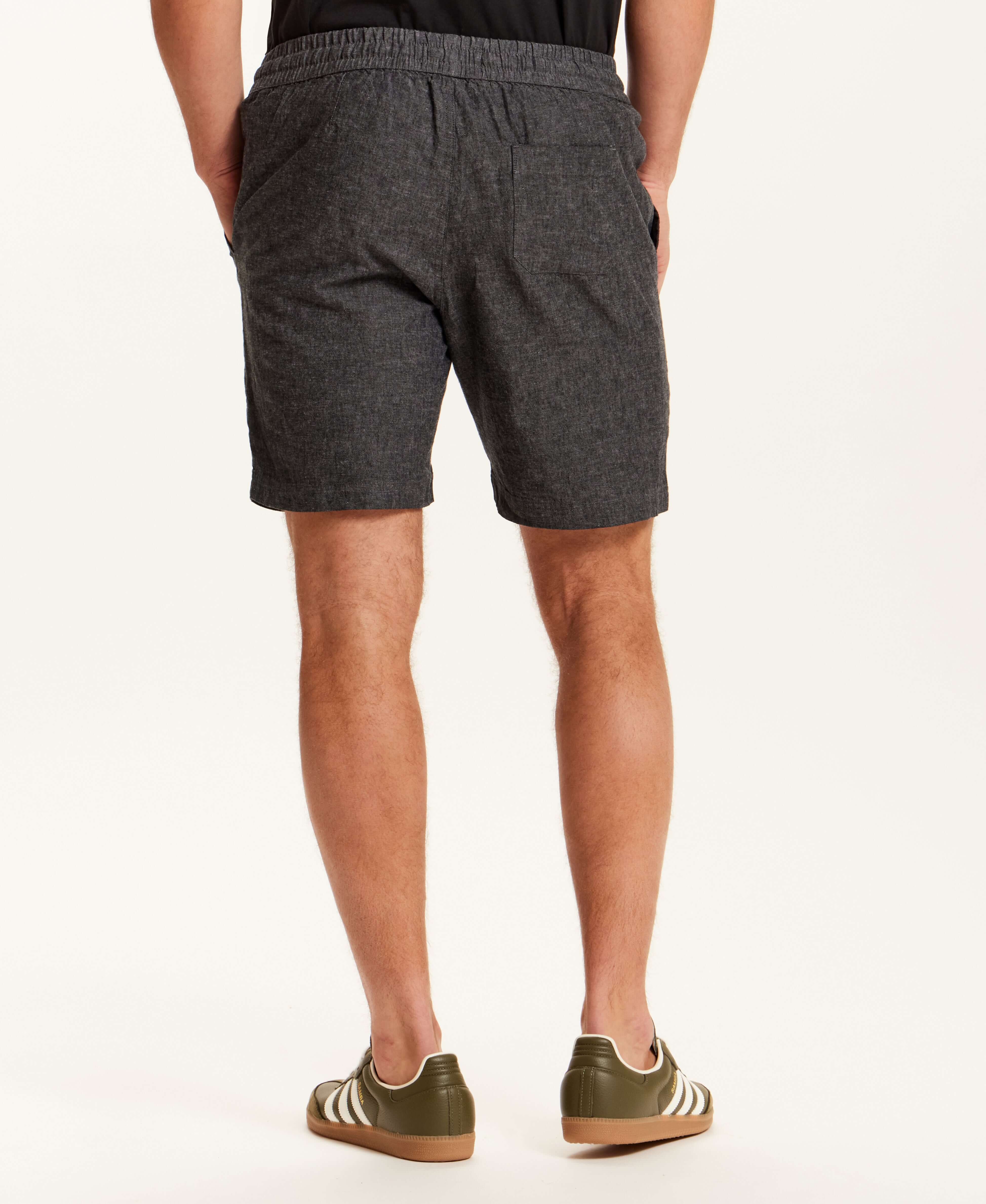 Back view of a man wearing Chambray Stripe Drawstring Short in Black with elastic waistband and side pockets.