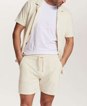 Model wearing Geometric Terry Camp Shirt in Stone, a relaxed button front shirt with geometric pattern and matching shorts.