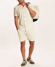 Model wearing the Geometric Terry Drawstring Short in Stone, paired with a matching shirt and carrying a tote.