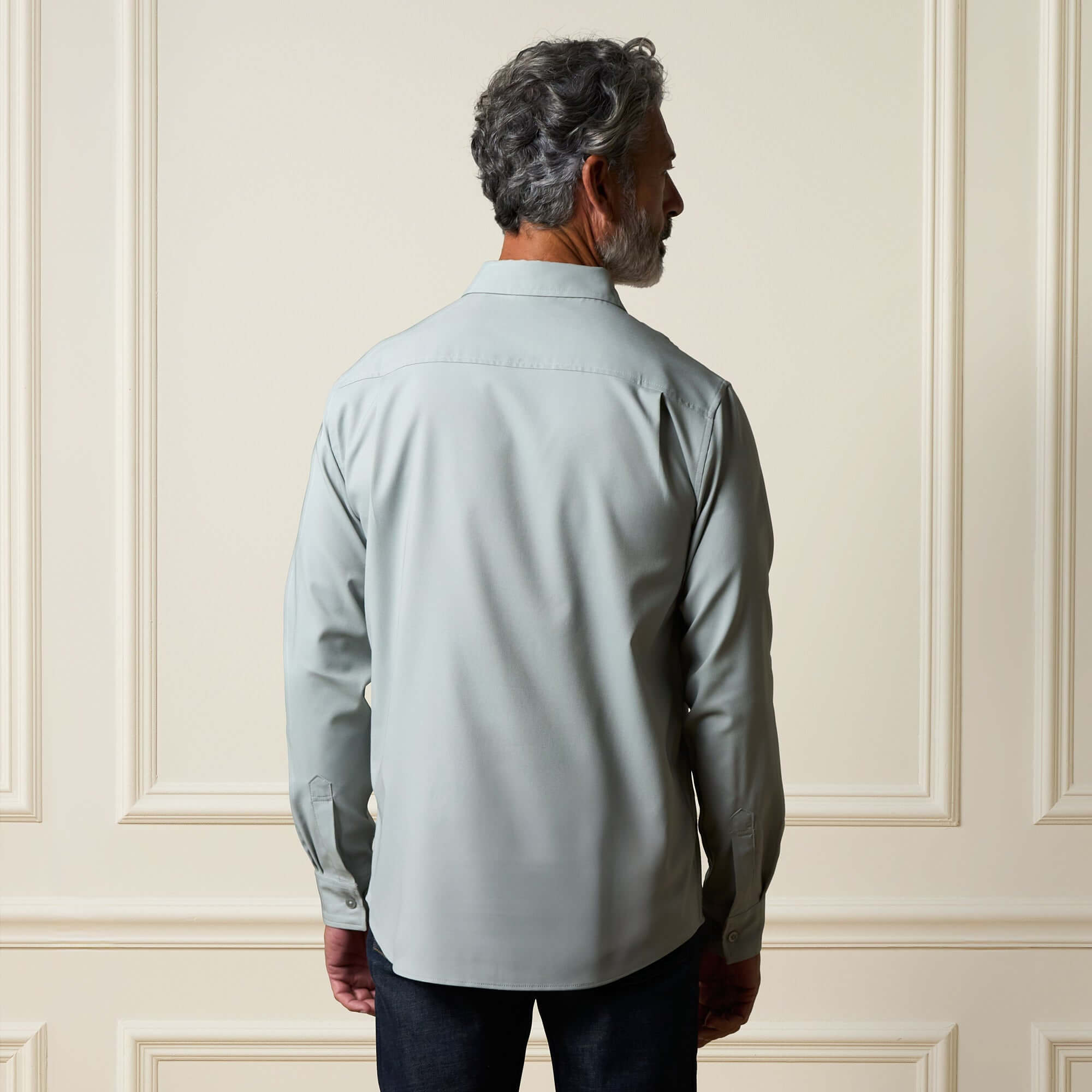 Man wearing a Long Sleeve Shirt in Medium Grey, showing the back view, highlighting its clean silhouette and button cuffs.