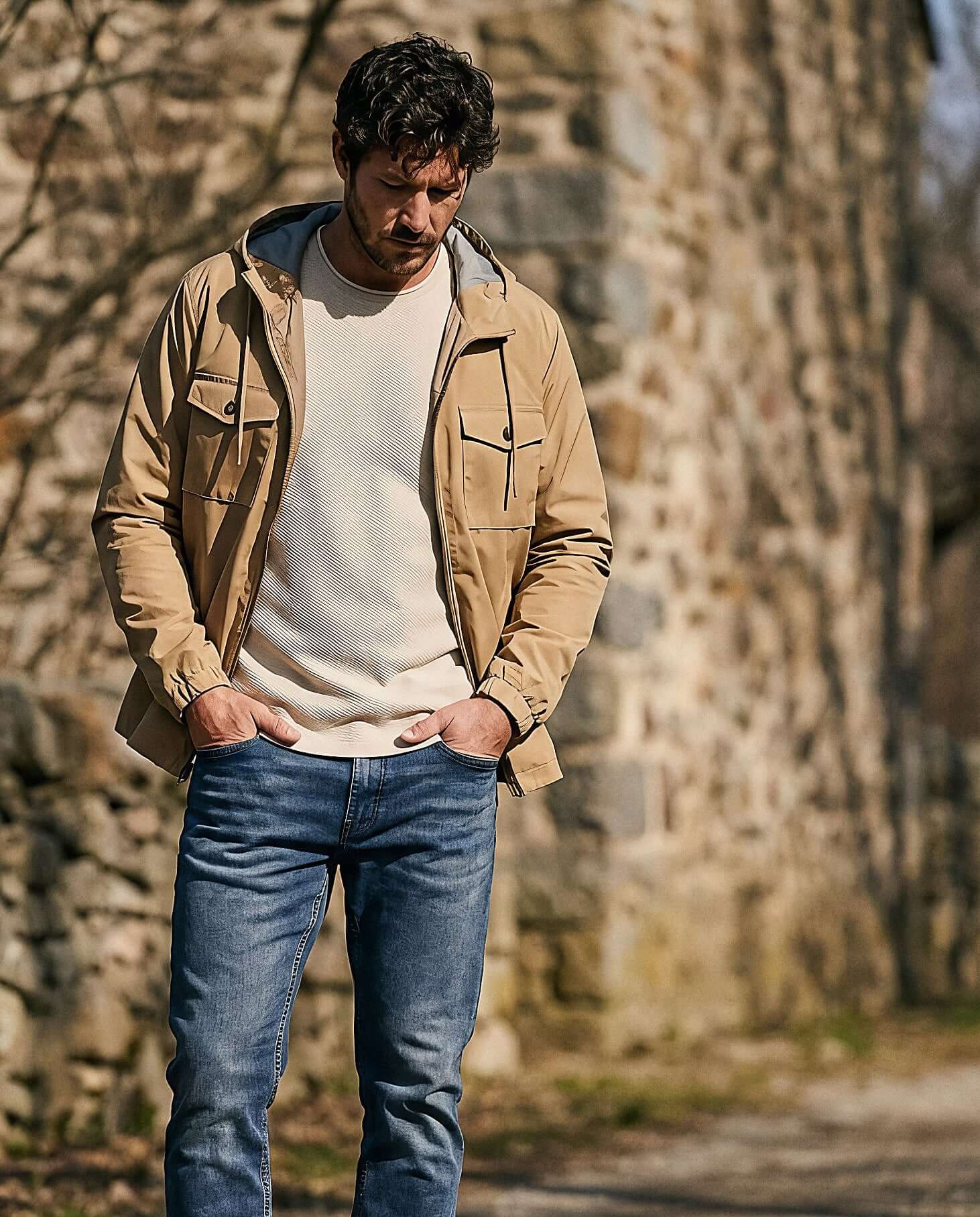 Poly Memory Safari Jacket with Hood in Kelp worn by a man outdoors, showcasing lightweight and stylish design.